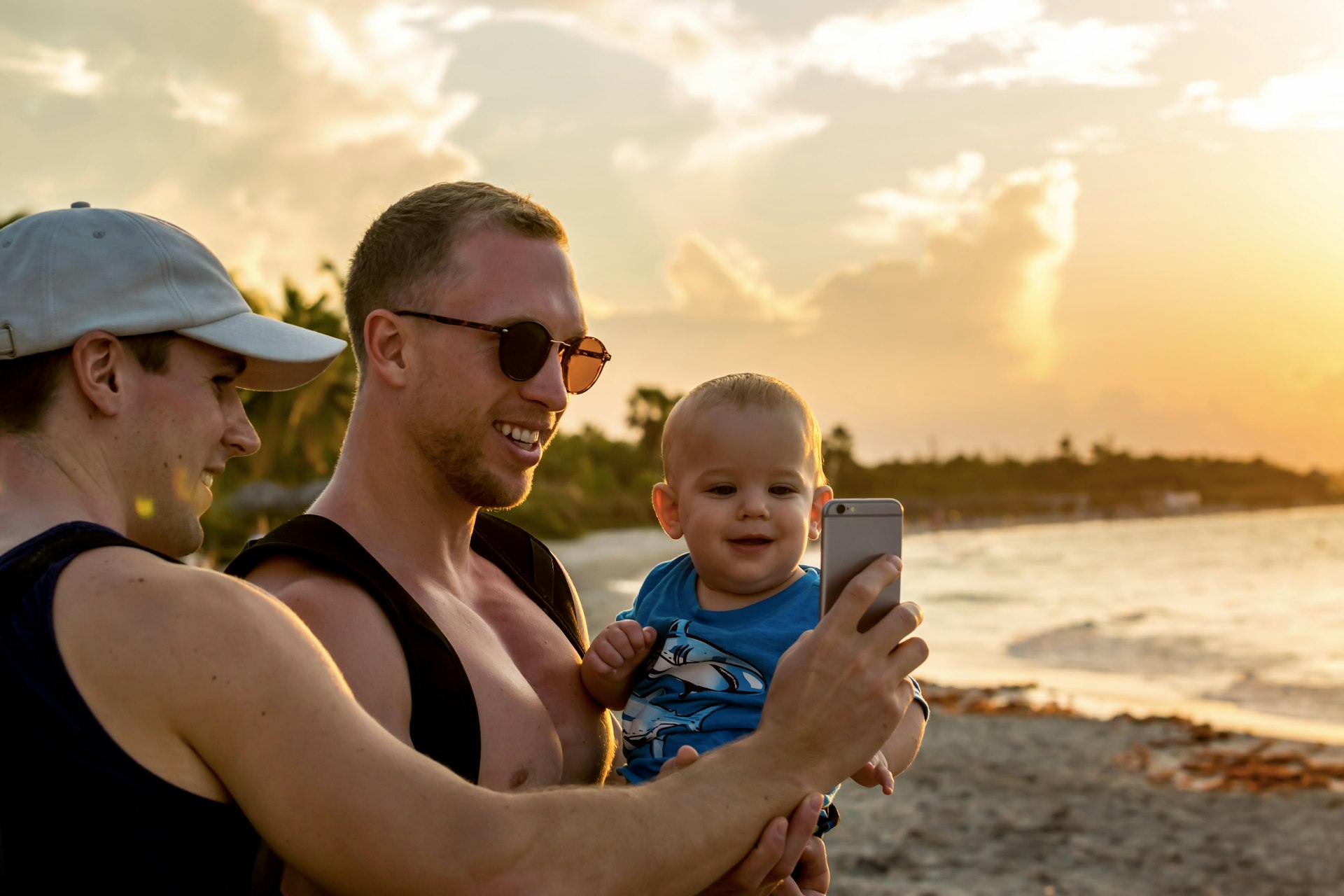 Two dads take a selfie with their baby on the beach, Varadero, Cuba