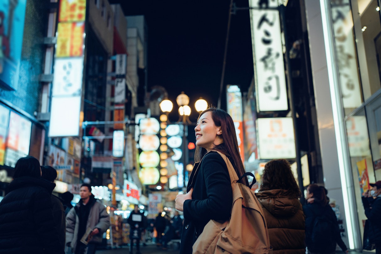 Smiling young Asian female traveller exploring and strolling along the busy and colourful neon signboard downtown city street at night in Osaka, Japan
1202888936