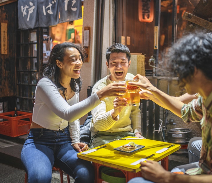 Young Japanese and mixed race friends in 20s laughing and toasting good news outdoors at Tokyo izakaya.
1227451731