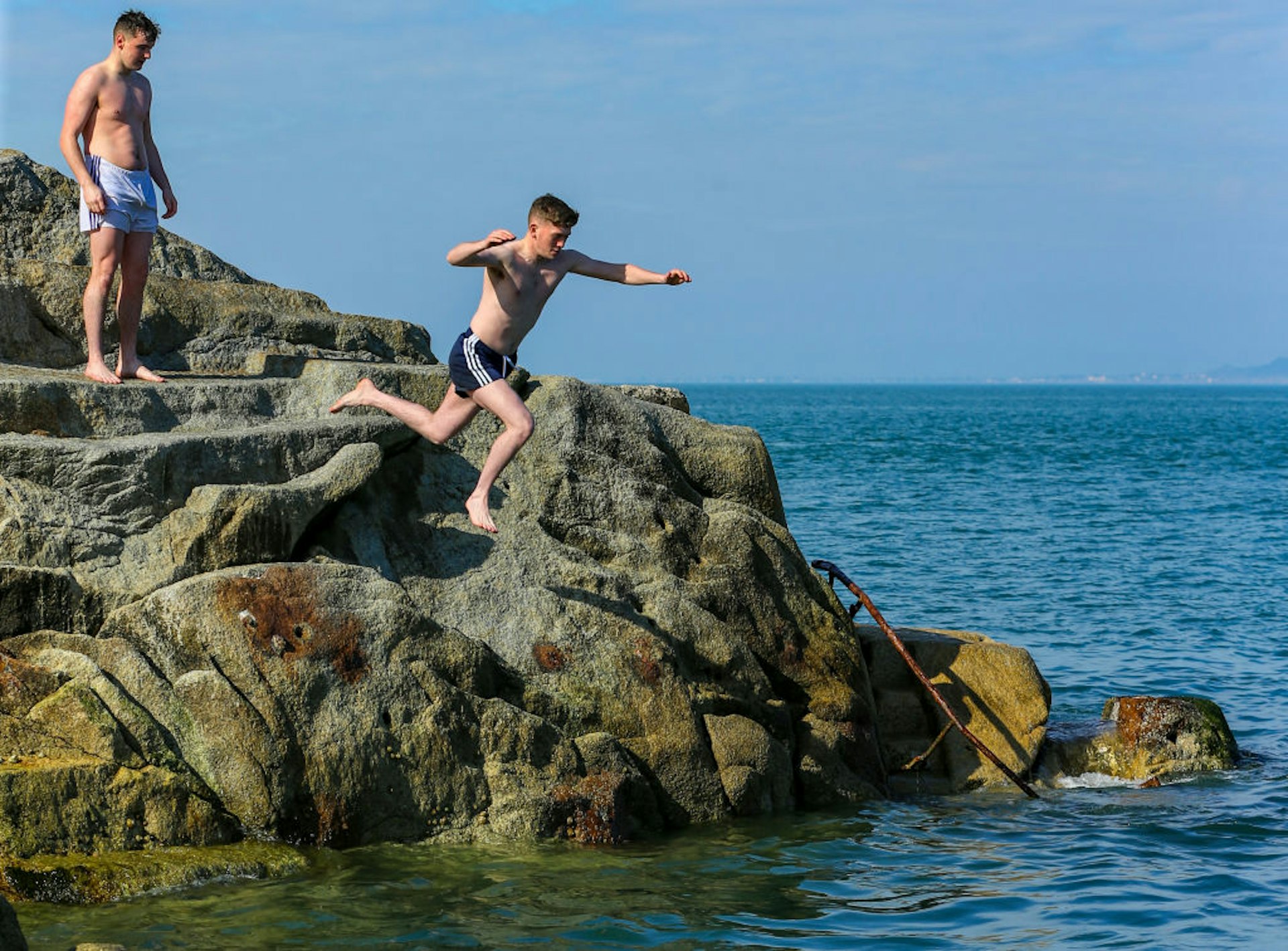 People take turns in jumping off of the rocks at the Forty foot in South Dublin on Thursday during good weather