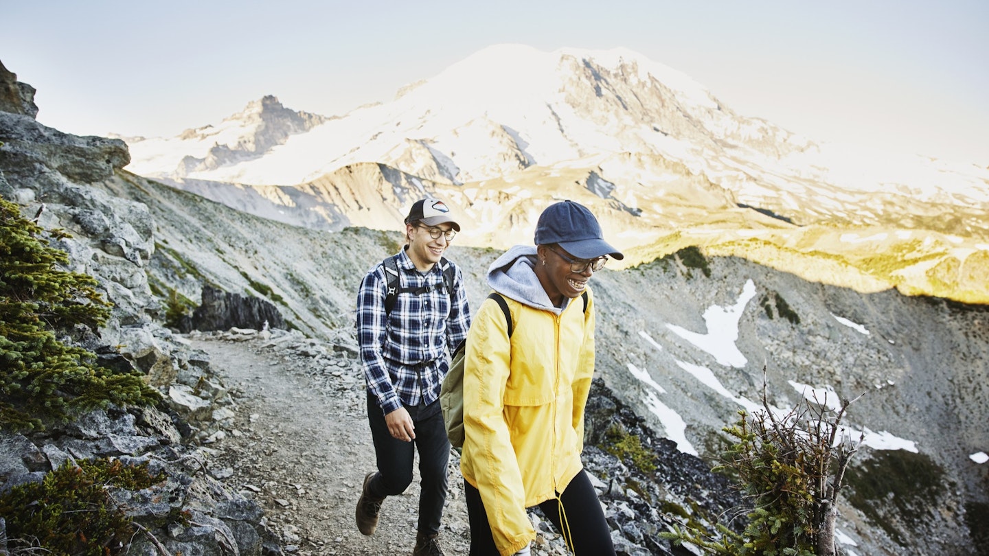 1287678994
Smiling couple hiking on alpine trail with Mt Rainier in background