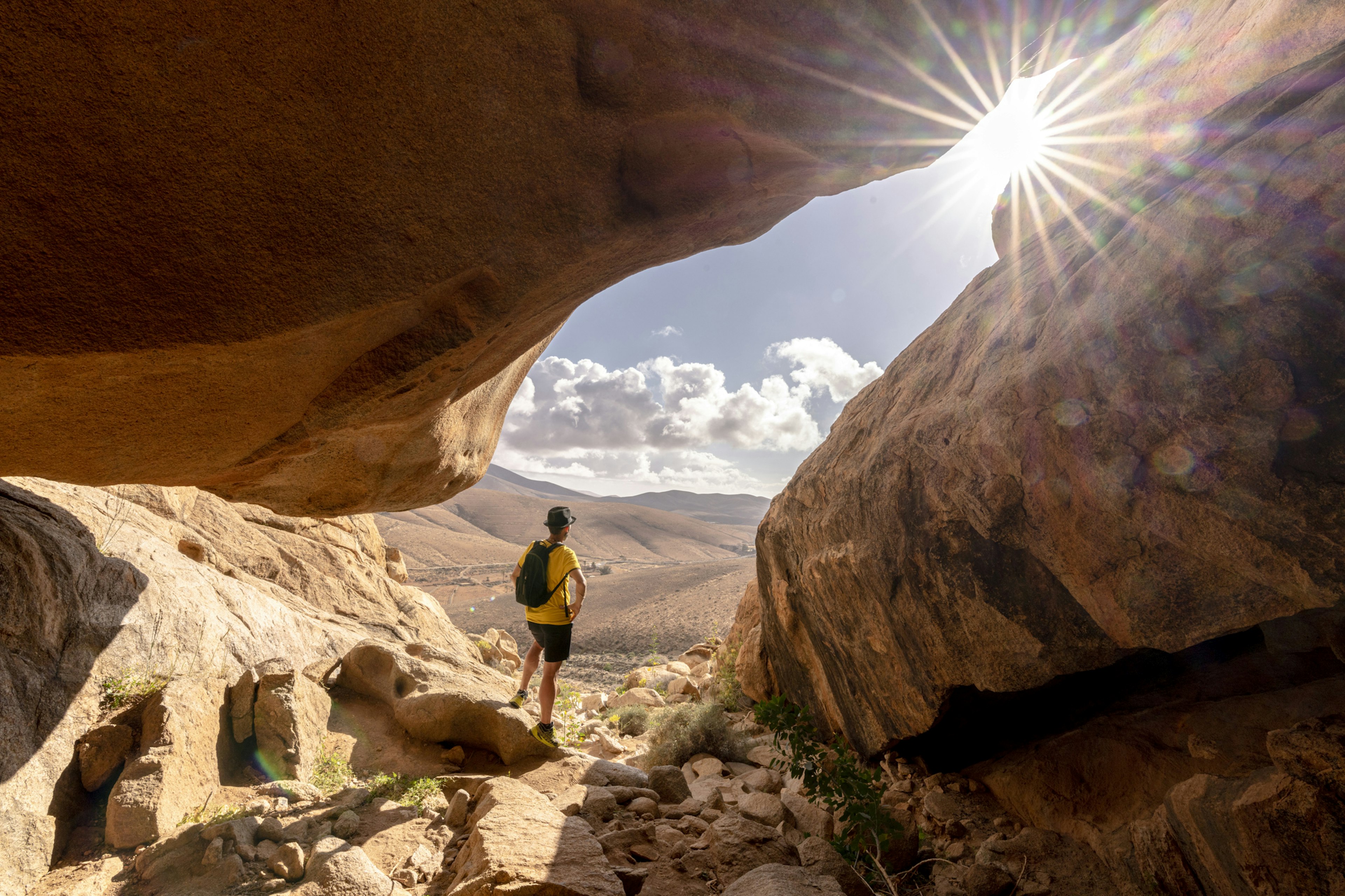 Person watching the sun standing inside a sandstone rock cave, Barranco de las Penitas, Fuerteventura, Canary Islands, Spain