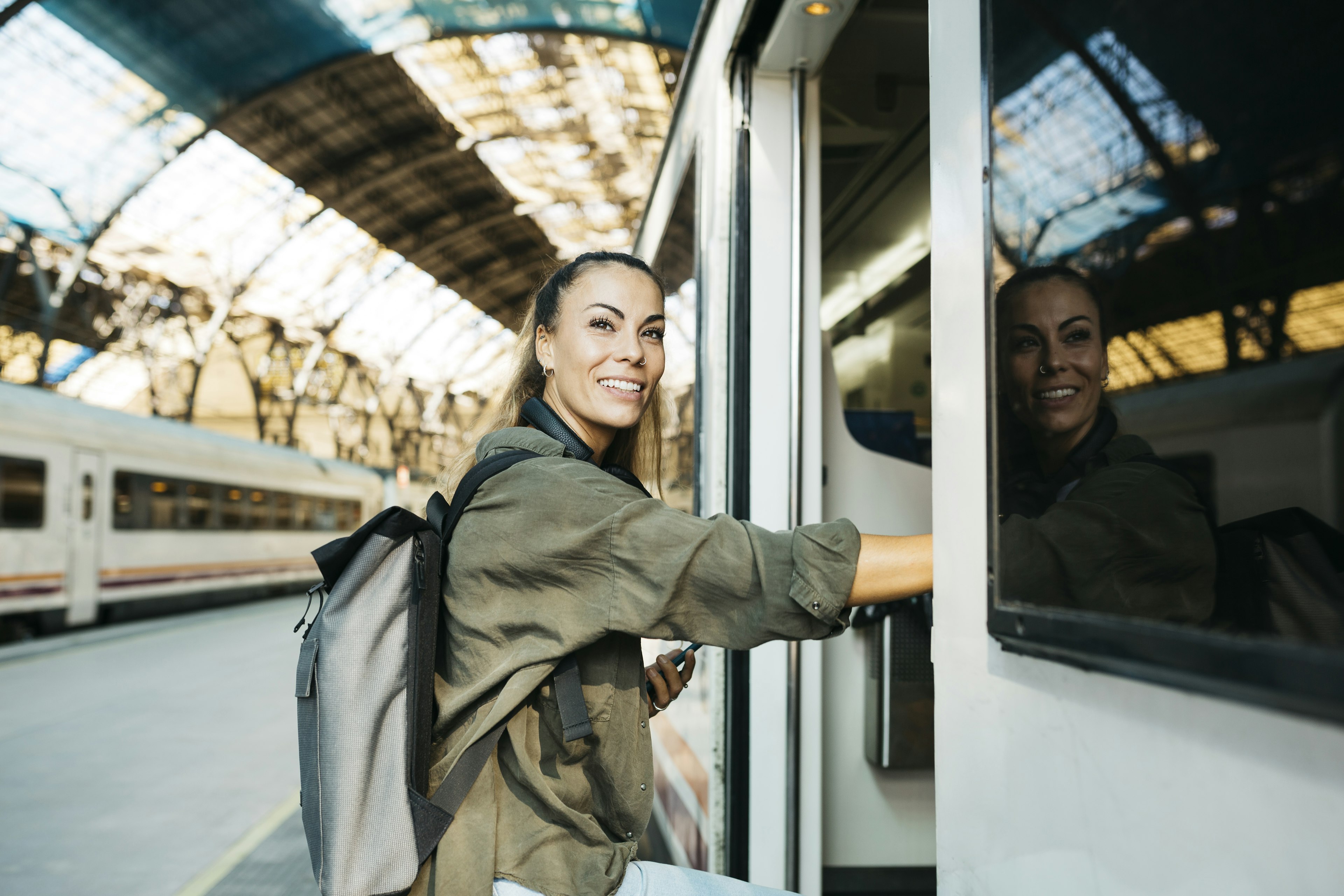 Young woman getting in a train before departure at the railroad station