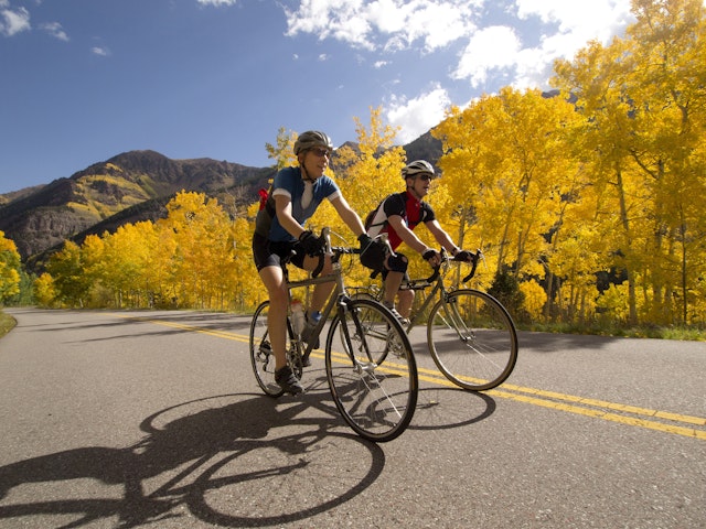 Two men cycling by fall foliage, Aspen, Colorado, USA