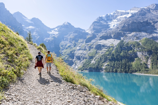 Two men hiking in a beautiful alpine scenery in Summer walking in the Swiss Alps enjoying nature and the outdoors - stock photo
Berner Oberland canton, Switzerland They walk on a trail along a beautiful blue lake in the center of Switzerland © Mystockimages / Getty