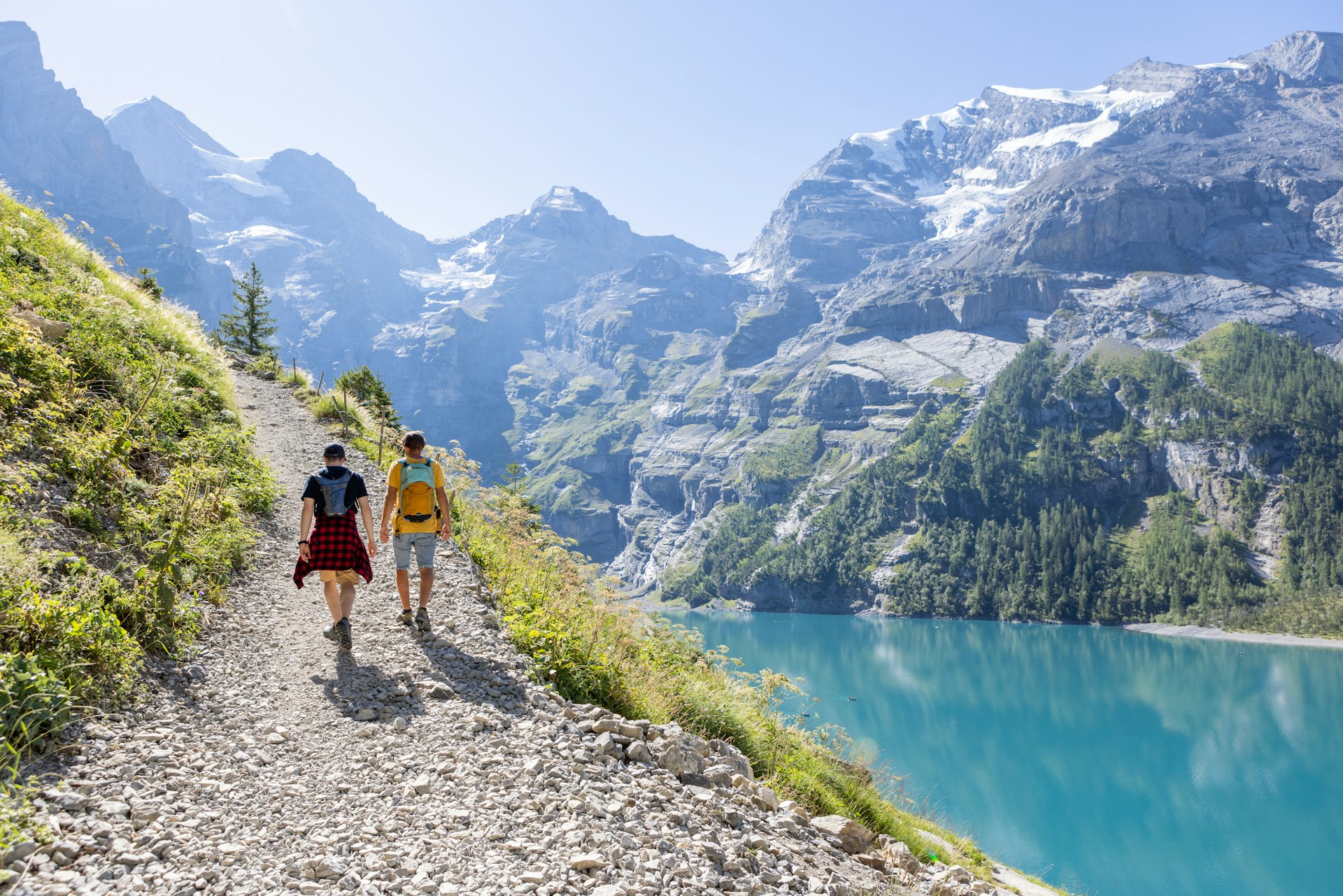 Two men hiking in a beautiful alpine scenery in Summer walking in the Swiss Alps enjoying nature and the outdoors