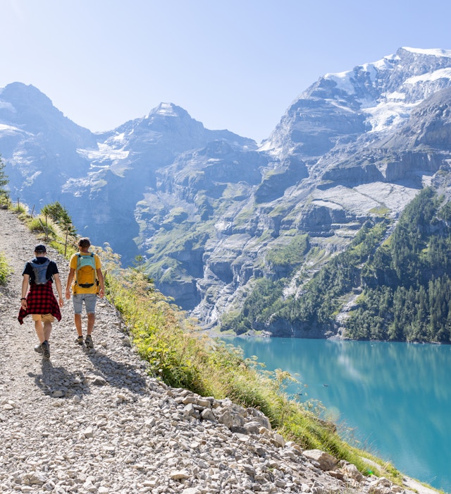 Two men hiking in a beautiful alpine scenery in Summer walking in the Swiss Alps enjoying nature and the outdoors - stock photo
Berner Oberland canton, Switzerland They walk on a trail along a beautiful blue lake in the center of Switzerland © Mystockimages / Getty