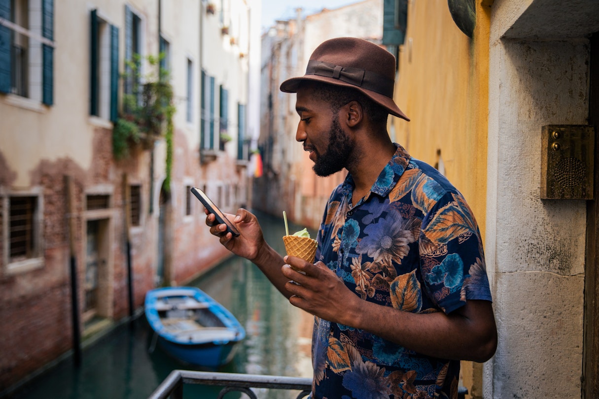 A tourist uses his smartphone while on holiday in Venice, stylish man with ice cream
1480867746