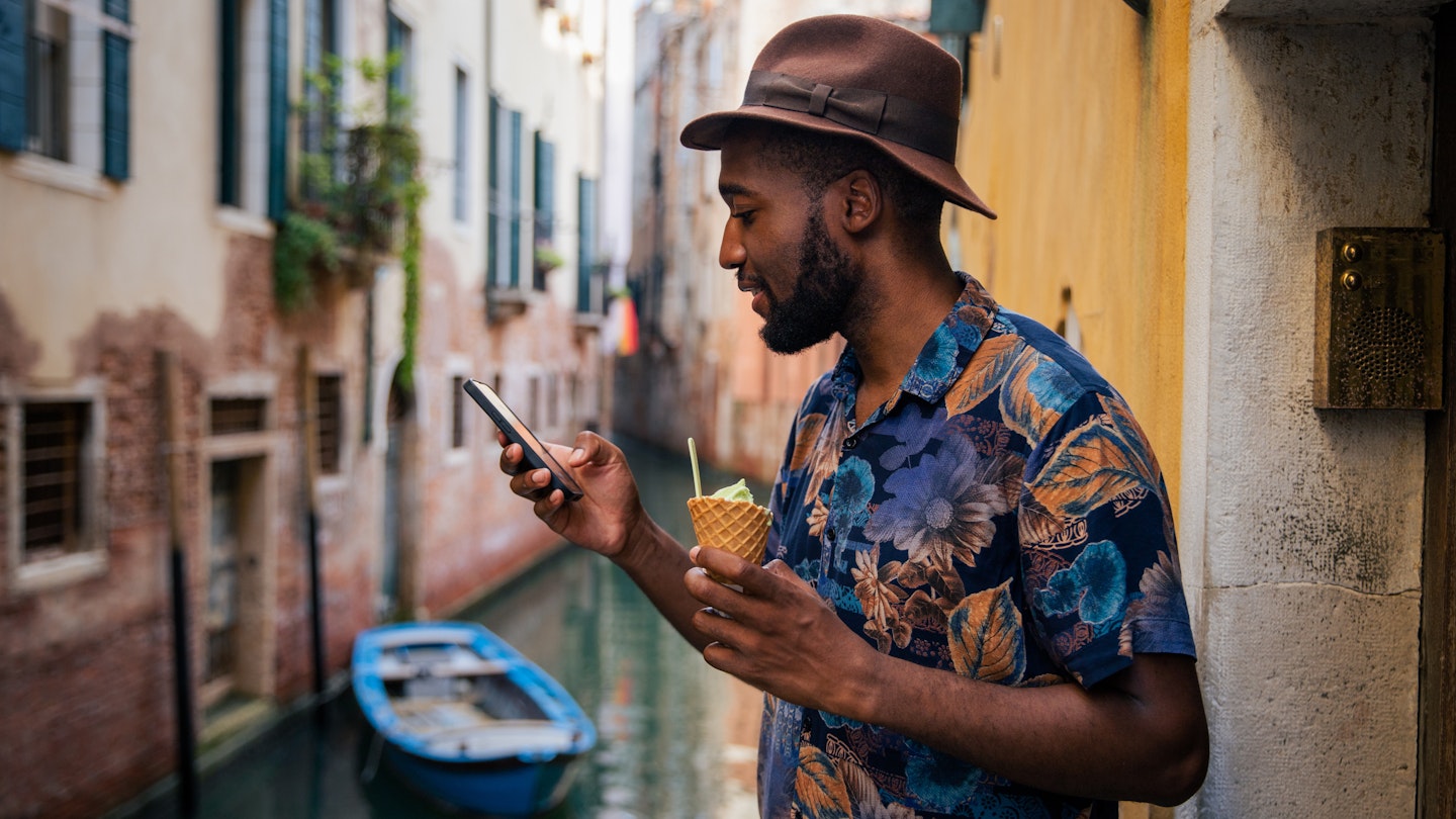 A tourist uses his smartphone while on holiday in Venice, stylish man with ice cream
1480867746