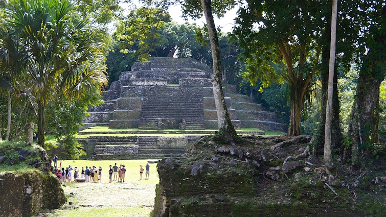 Wide shot of tourists dwarfed by the Temple of the Jaguar Mayan pyramid in Lamanai, Belize
1481511269