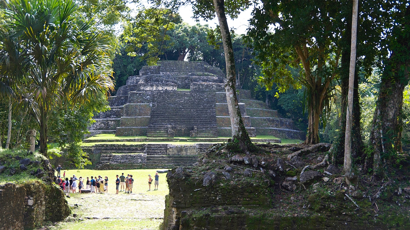 Wide shot of tourists dwarfed by the Temple of the Jaguar Mayan pyramid in Lamanai, Belize
1481511269