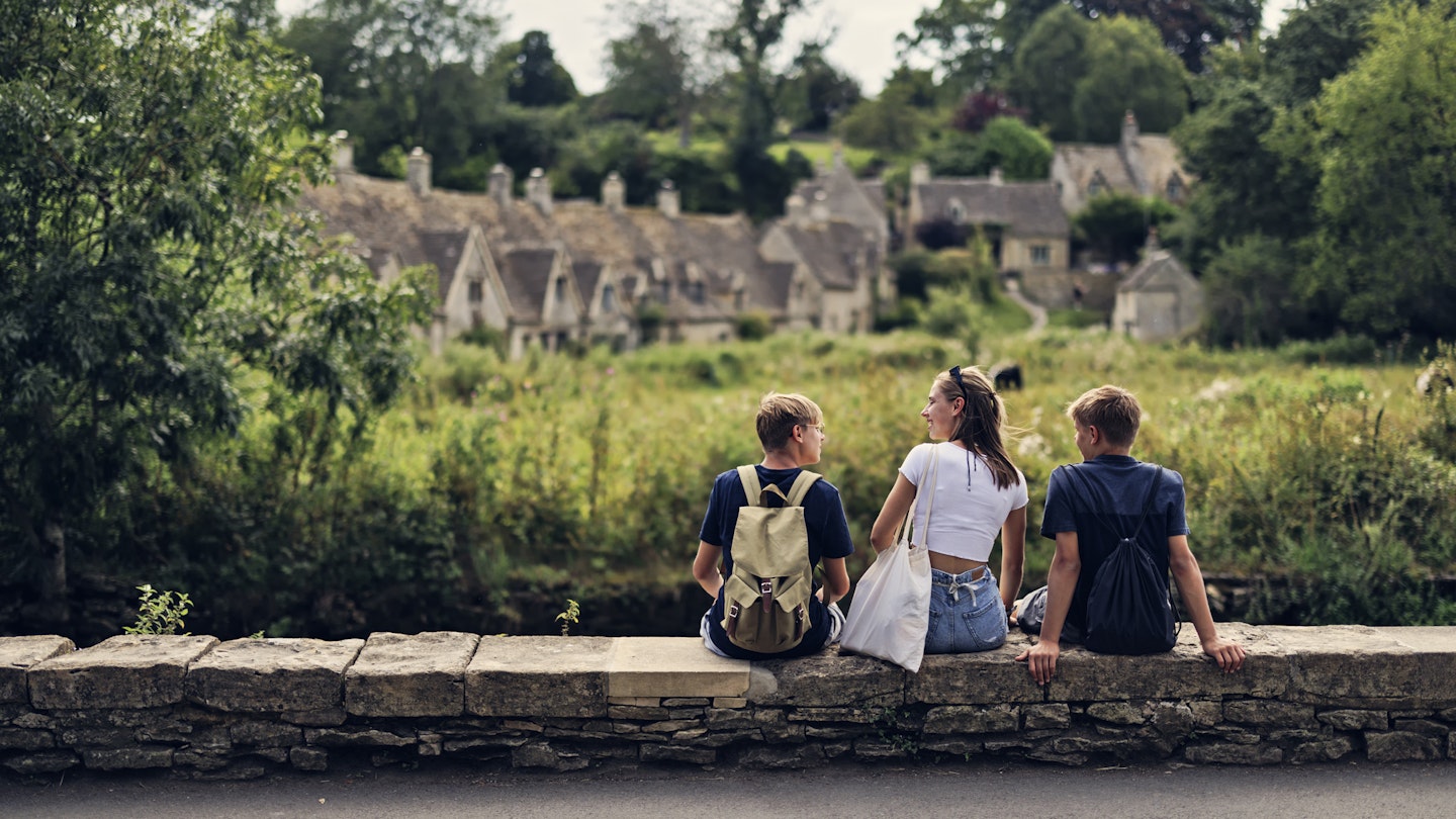 Three teenage kids enjoying summer vacations in Cotswolds, Gloucestershire, United Kingdom. ..They are sitting by the river and looking at the famous row of houses in Bibury...Shot with Canon R5
1667990110