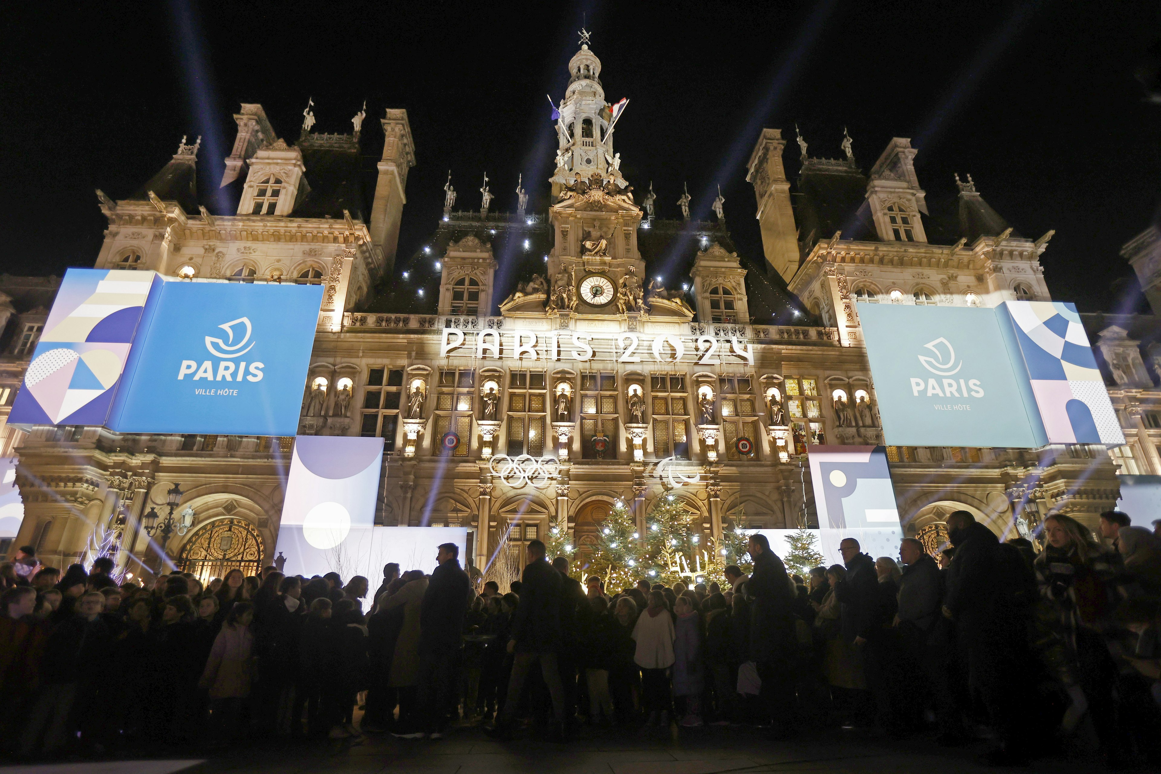 e logo, Paris 2024 representing the Olympic Games, several months prior to the start of the Paris 2024 Olympic and Paralympic Games is displayed on the illumined facade of Paris town hall.