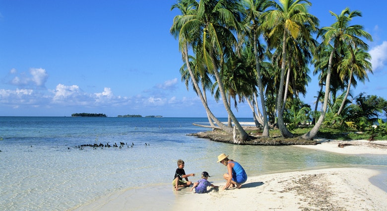 A mother and two kids playing on the beach in Belize