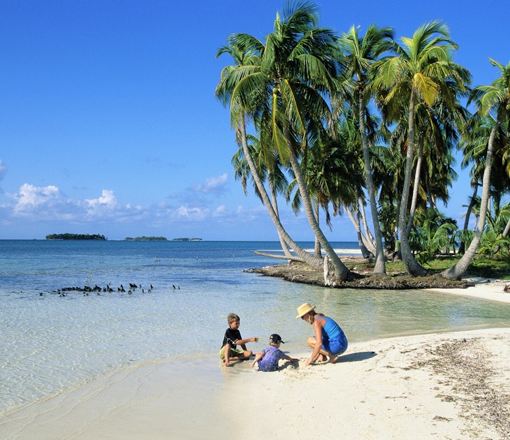 A mother and two kids playing on the beach in Belize