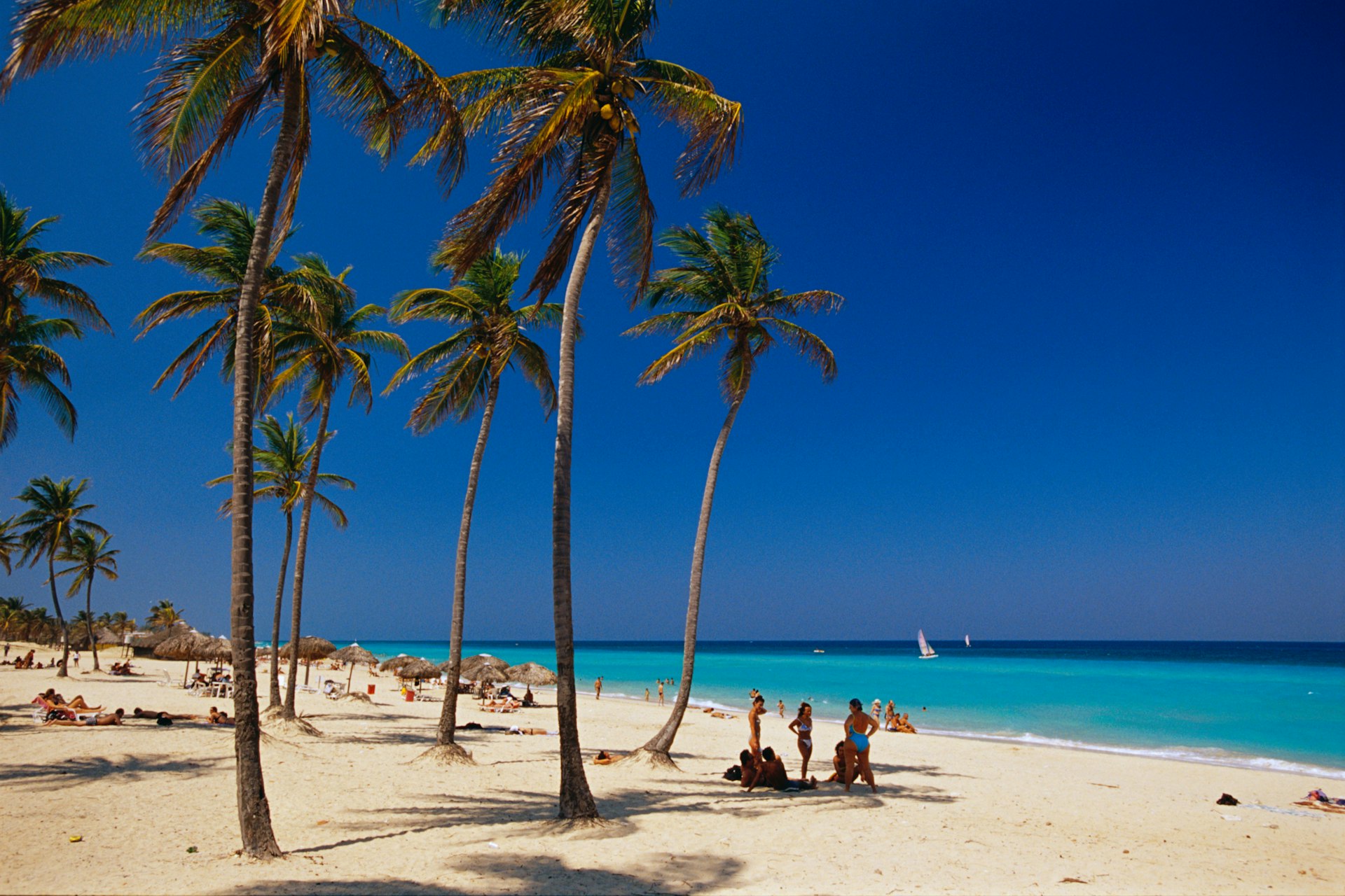 People lounge on the white sand of Santa María Beach in Cuba