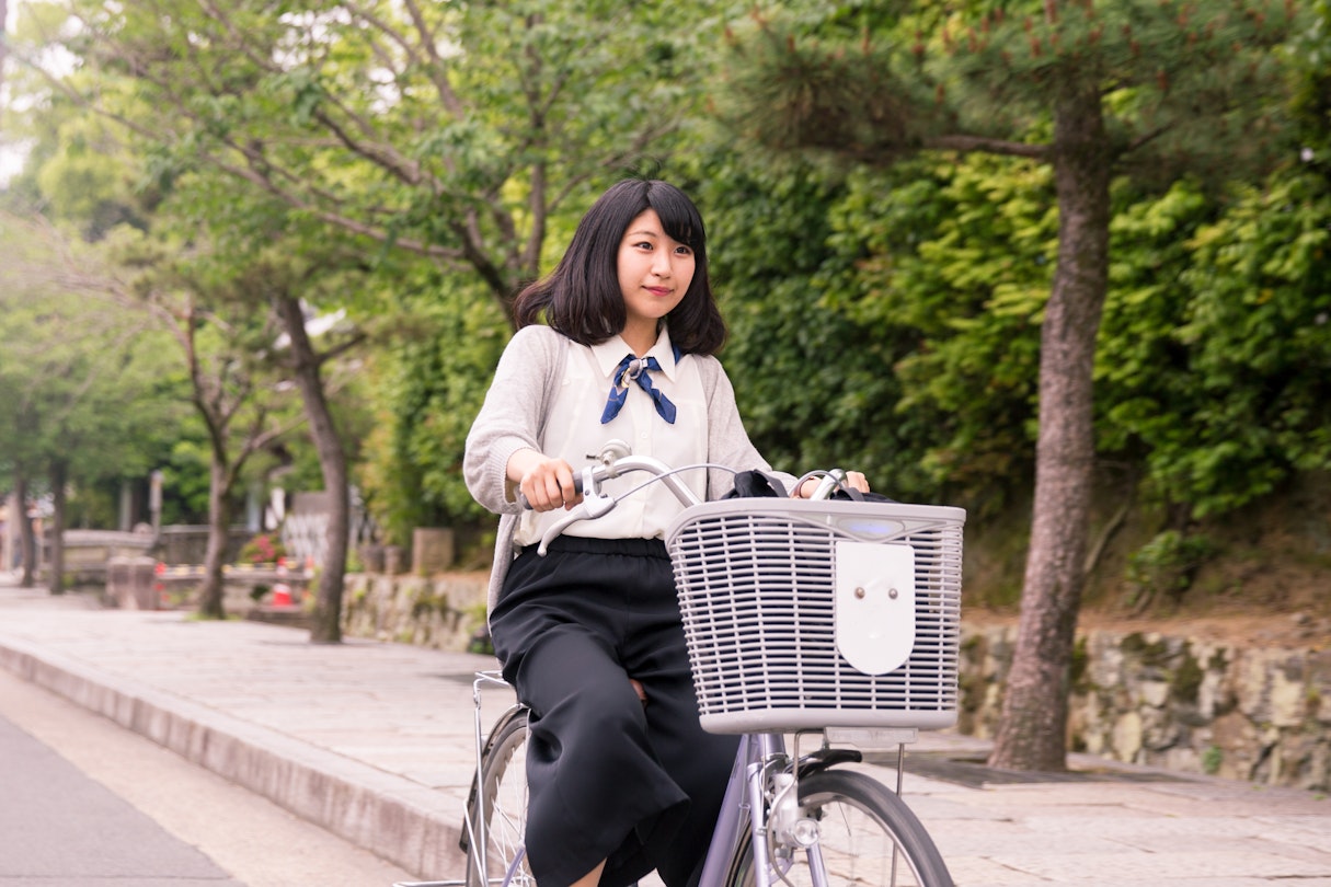 A young woman cycling through the streets of Kyoto