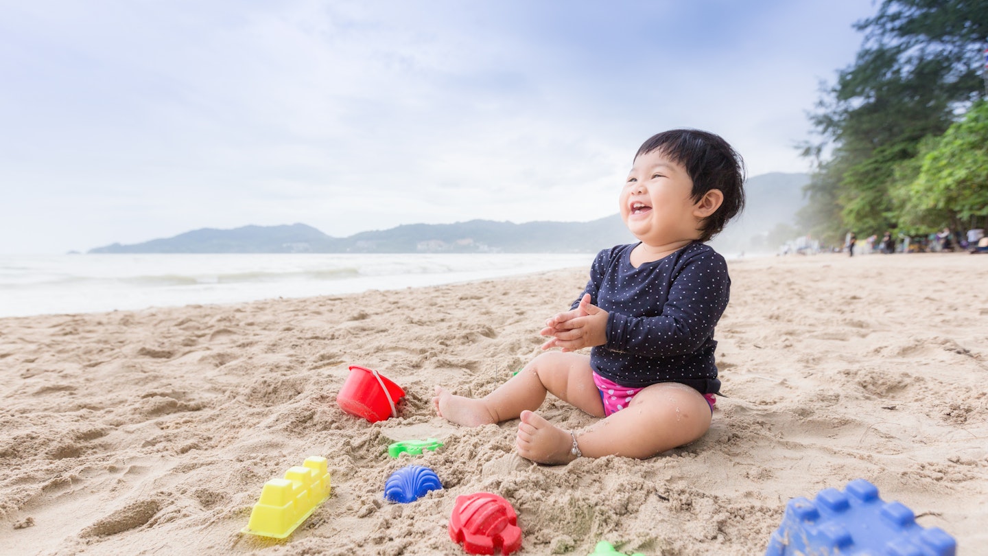 Baby girl laughing on the beach. Can use for learning and playing concept.
876796254