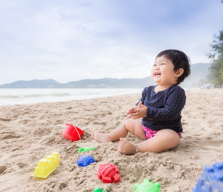 Baby girl laughing on the beach. Can use for learning and playing concept.
876796254