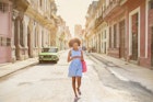 A woman walking along a street in Havana while looking at her phone