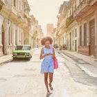 A woman walking along a street in Havana while looking at her phone