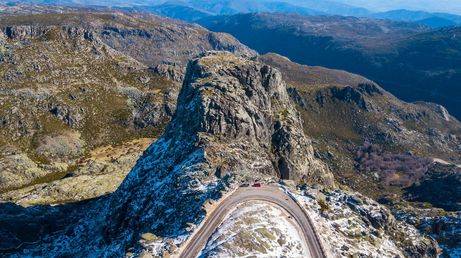 Rocky mountain pass in Serra da Estrela with cars parked on road side