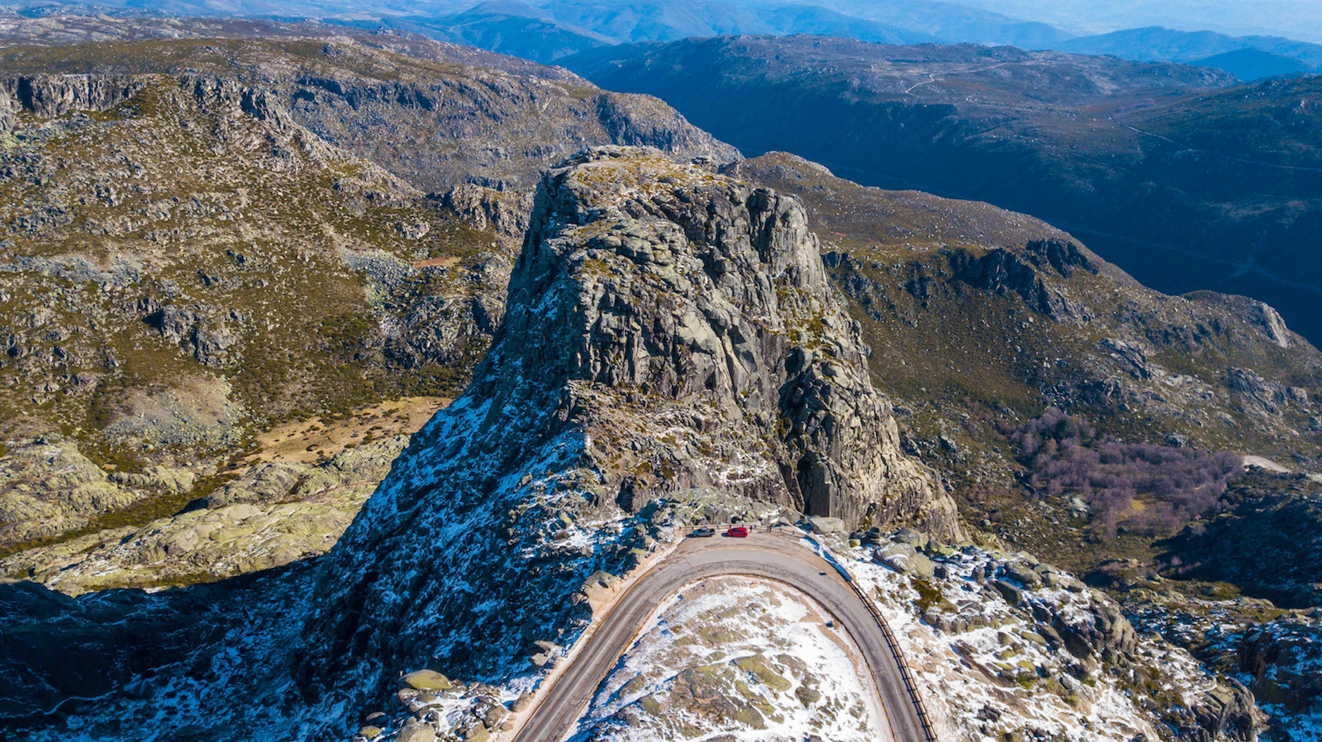Rocky mountain pass in Serra da Estrela with cars parked on road side