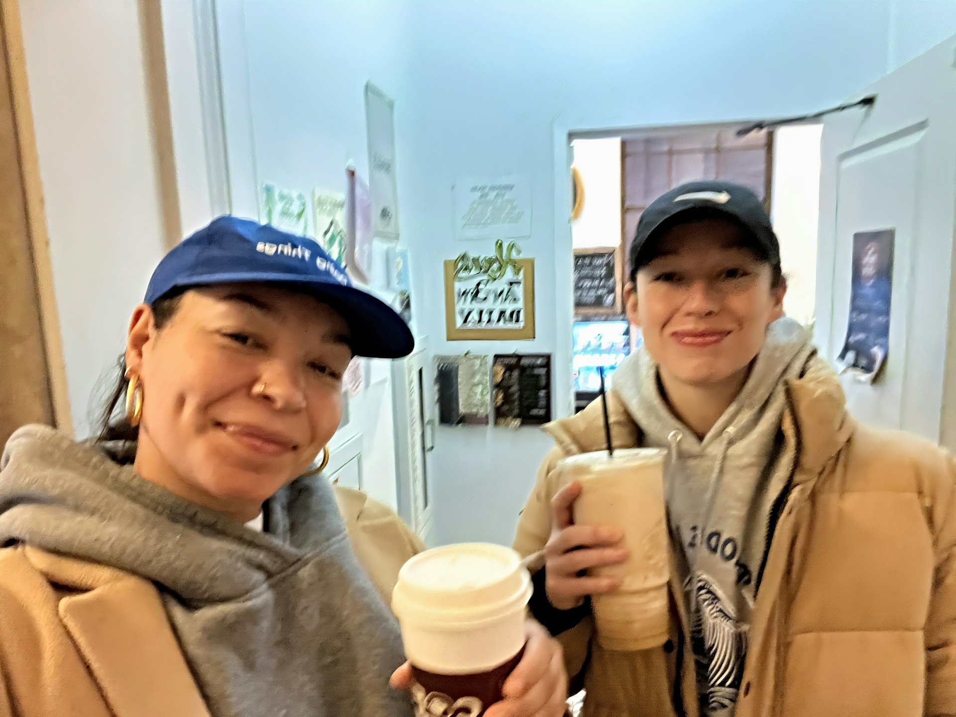 The article's author, Rachel, and her wife pose with coffees in a cafe in Providence