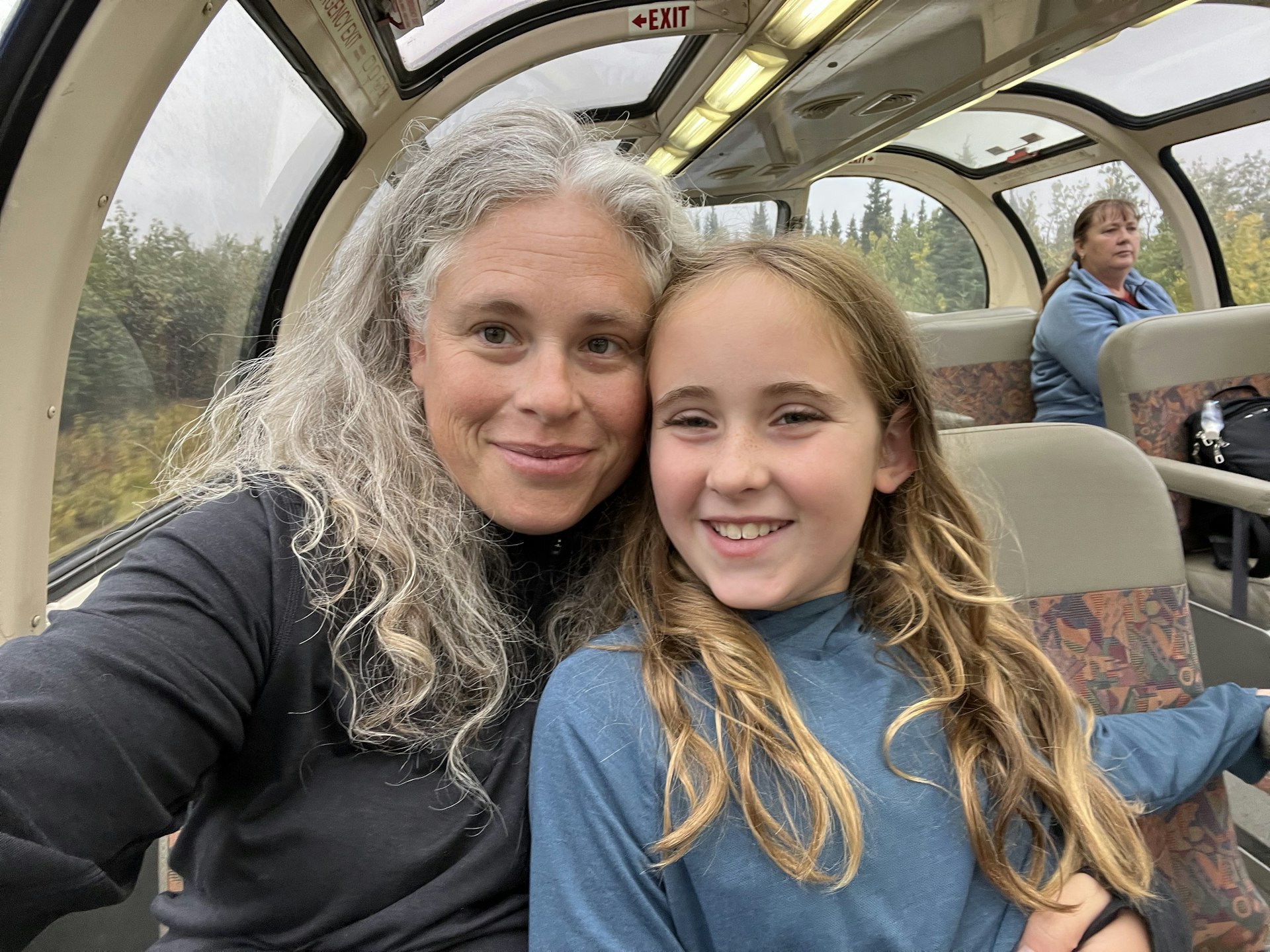 A escritora Sarah e sua filha sorriem para a câmera enquanto estão sentadas no trem Denali Star