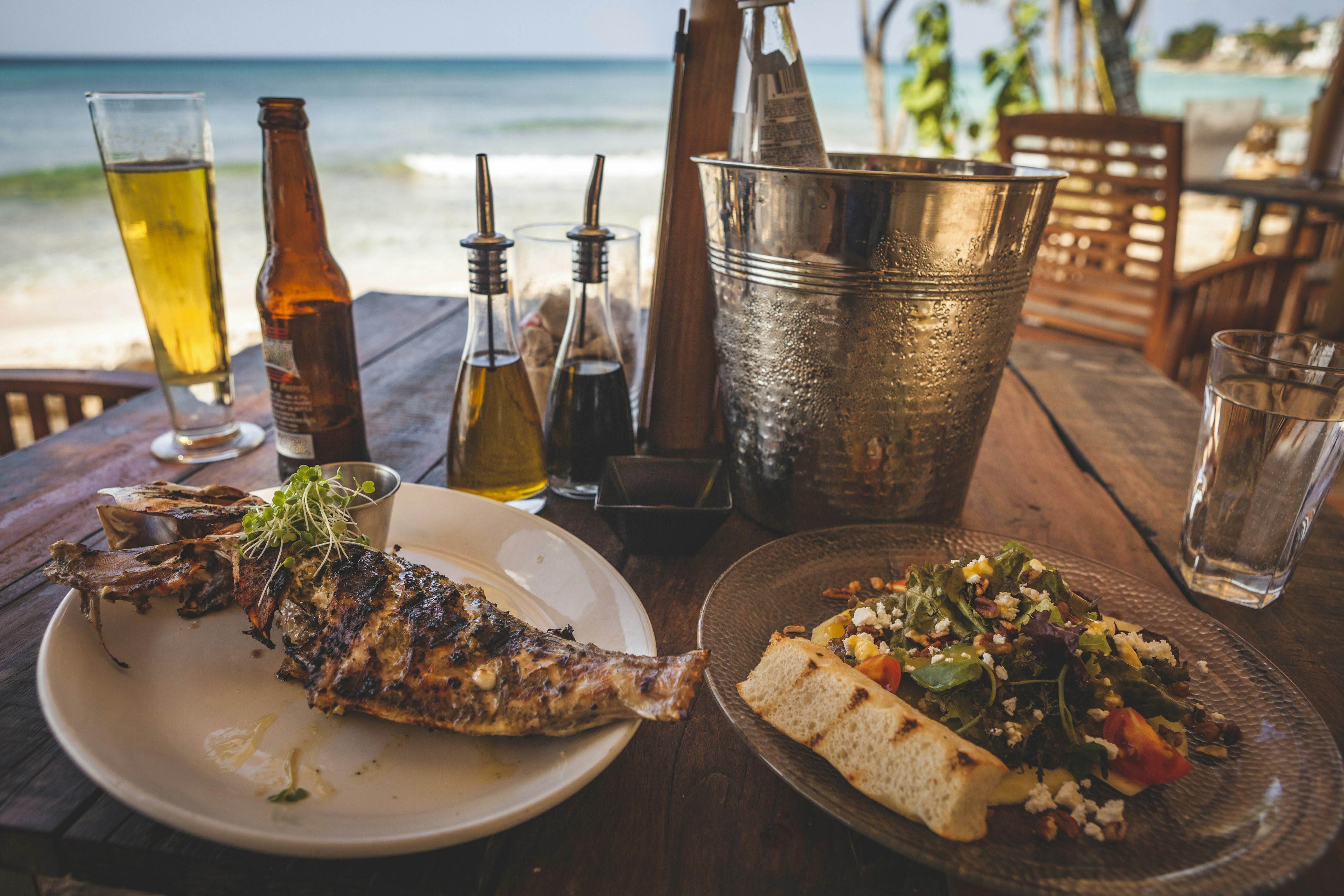 Grilled fish and salad lunch layed out on a beachside table in Barbados