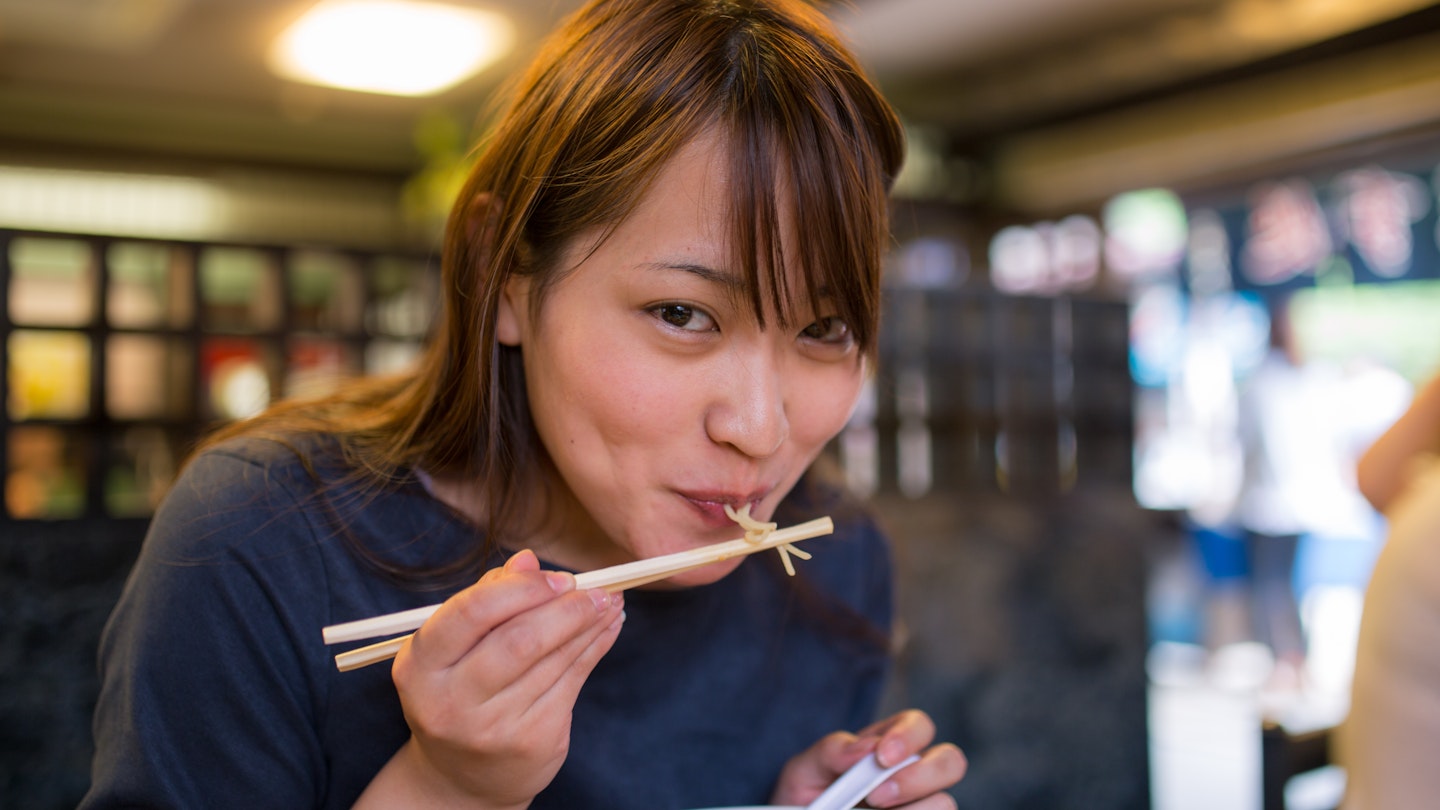 Young woman eating ramen noodle in old Japanese restaurant