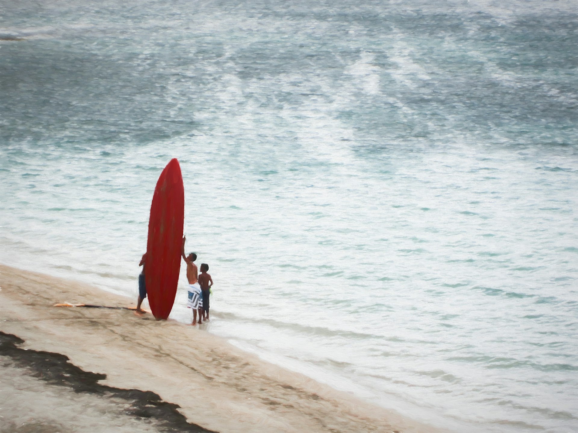 Children with a red surfboard at the beach
