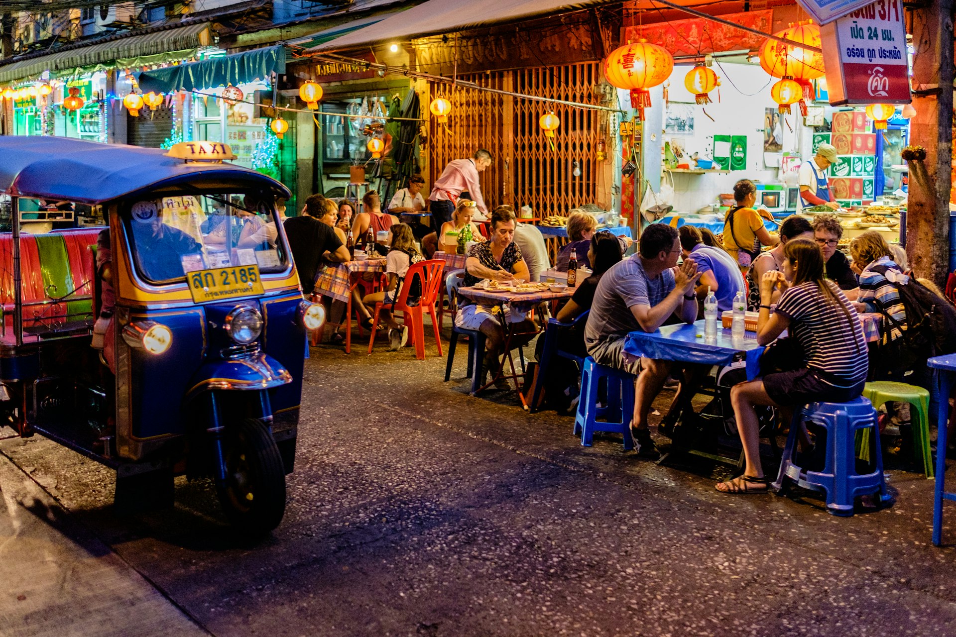 People sit at outside tables enjoying street food meals