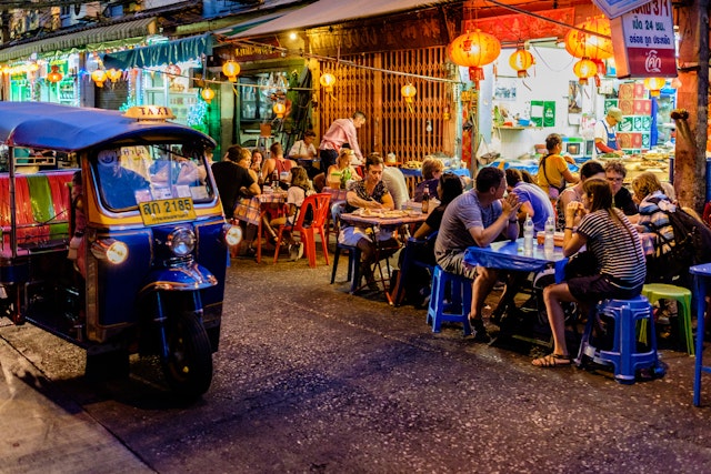 People sit at outside tables enjoying street food meals