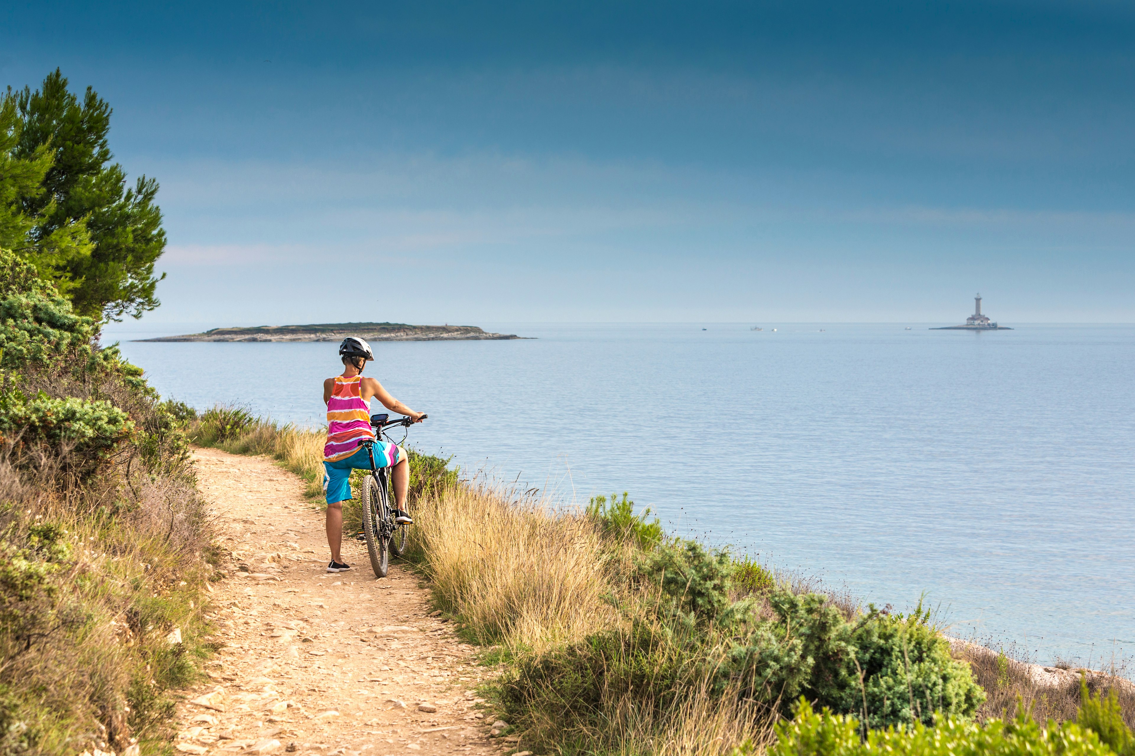 A cyclist pauses on a cliff path to take a look out to sea