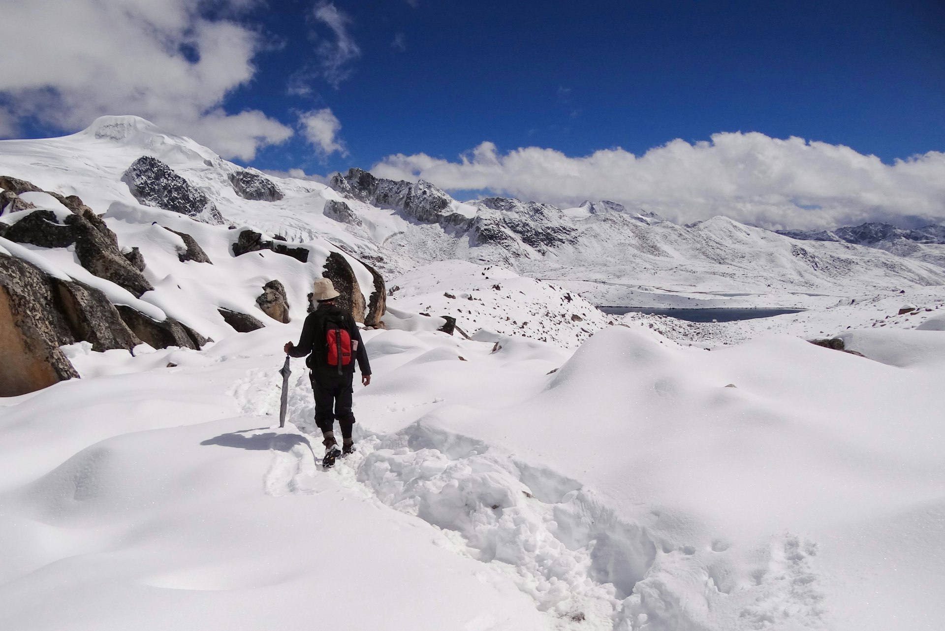 A man in snow gear walks through thick, heavy white snow in the Himalaya as part of Bhutan's Snowman Trek