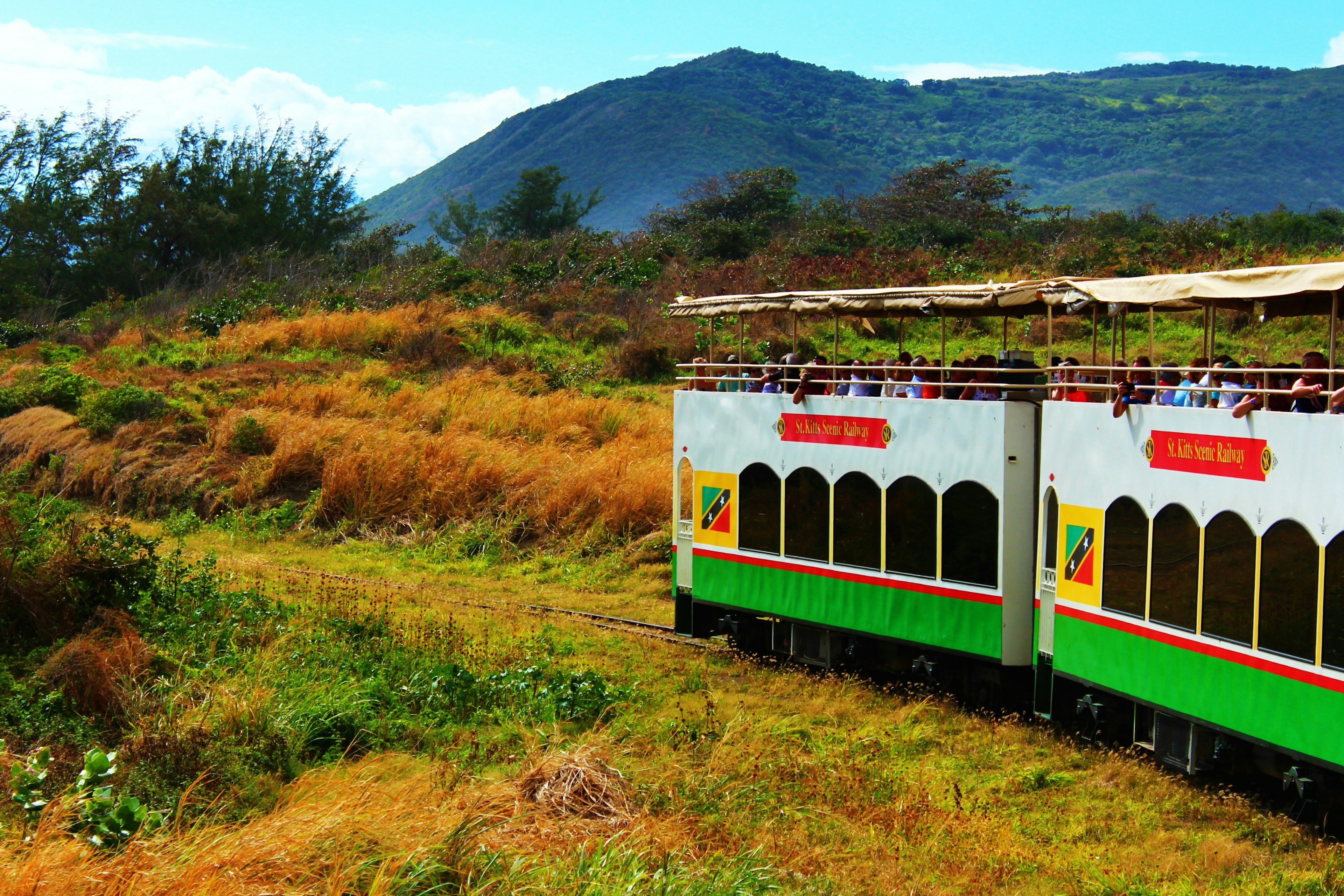 People ride along in double-decker train carriages with open-air top decks so they can watch the scenery go by