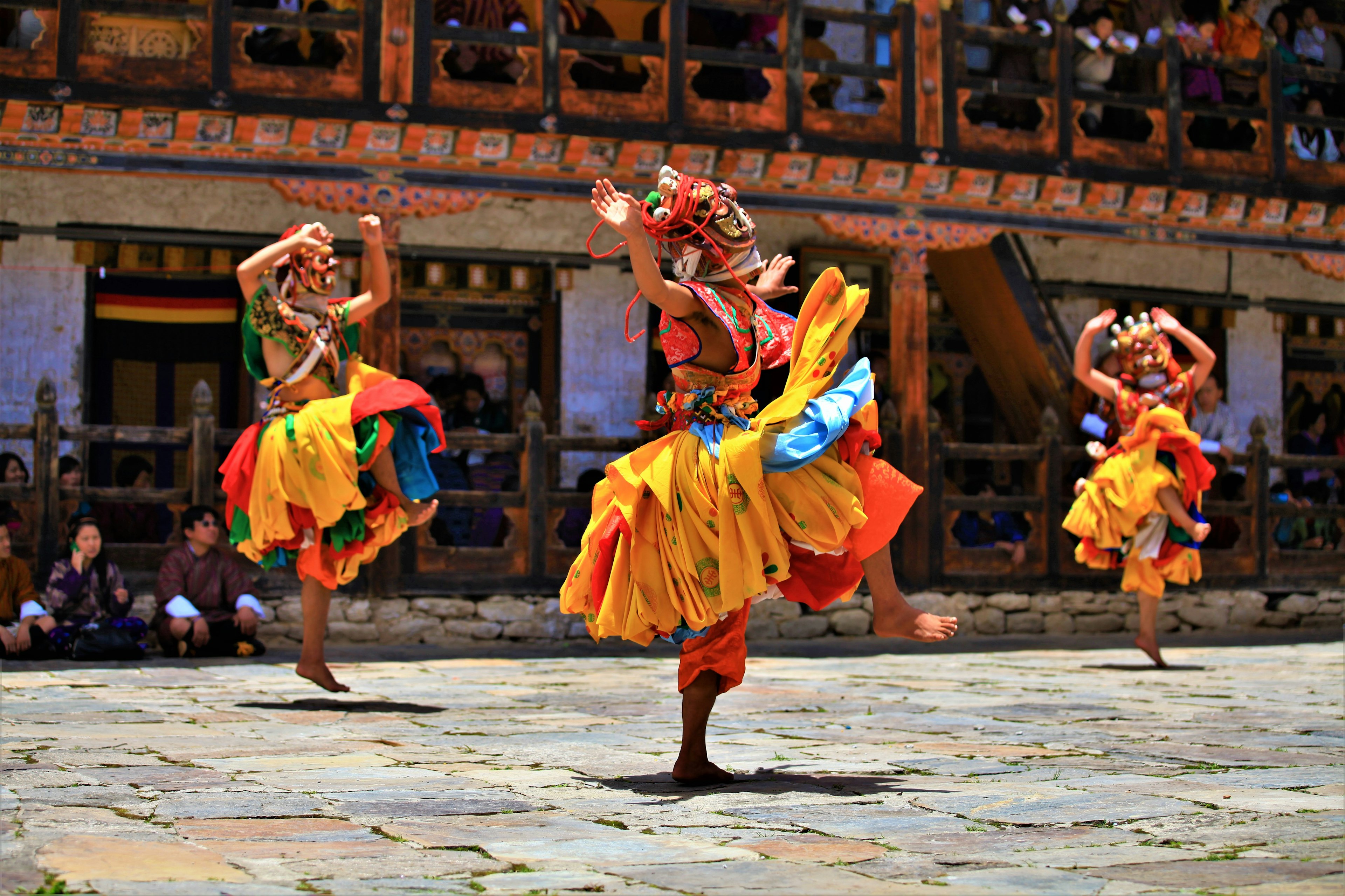 Monks wearing brightly colored costumes dance in a festival