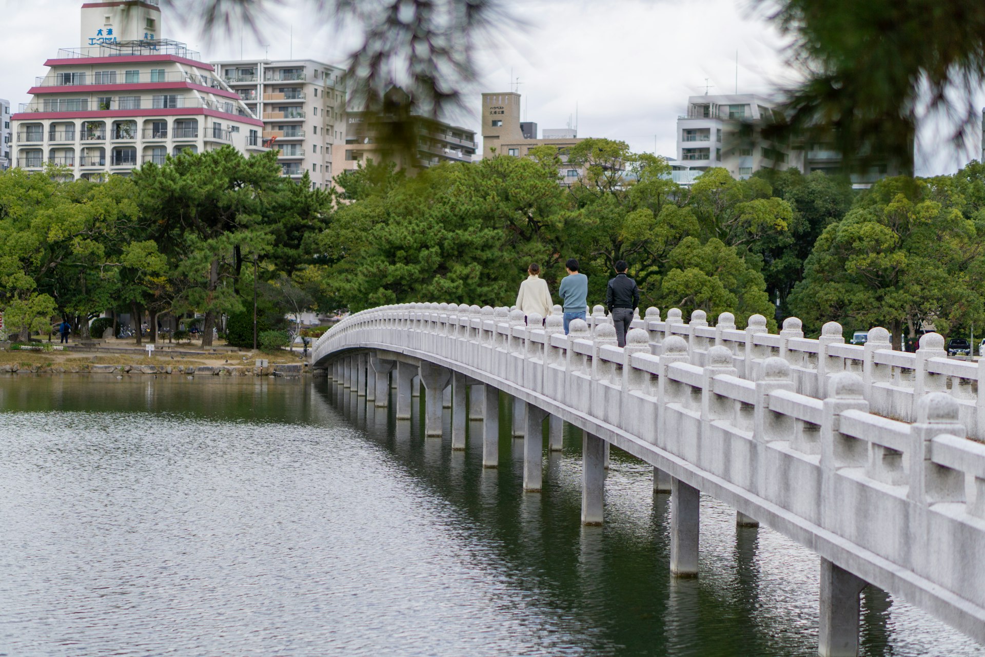 People walk across Kangetsu Bridge in Ōhori Park, Fukuoka, Japan