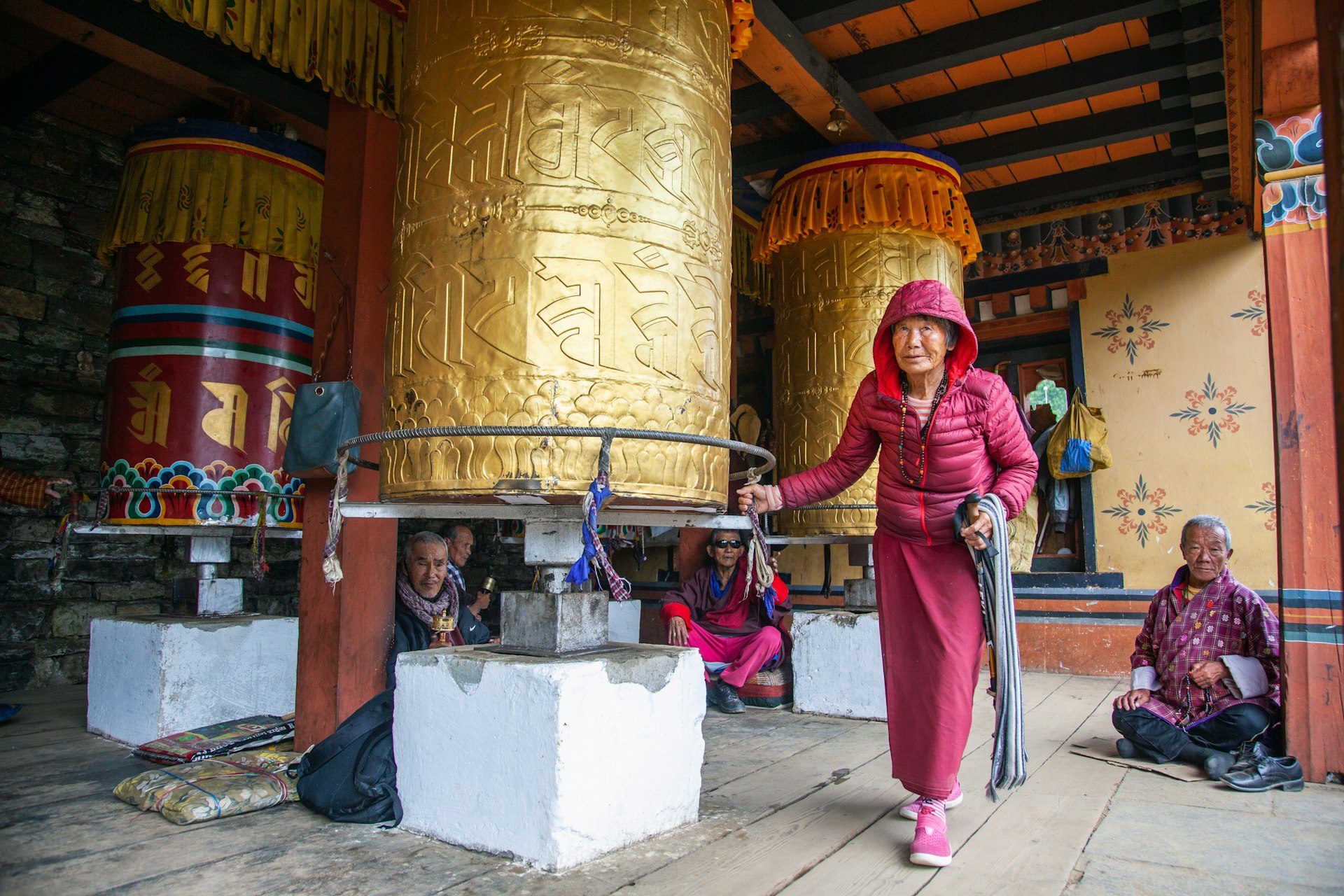 An old woman spinning a big prayer wheel at National Memorial Chorten complex in Thimphu, Bhutan