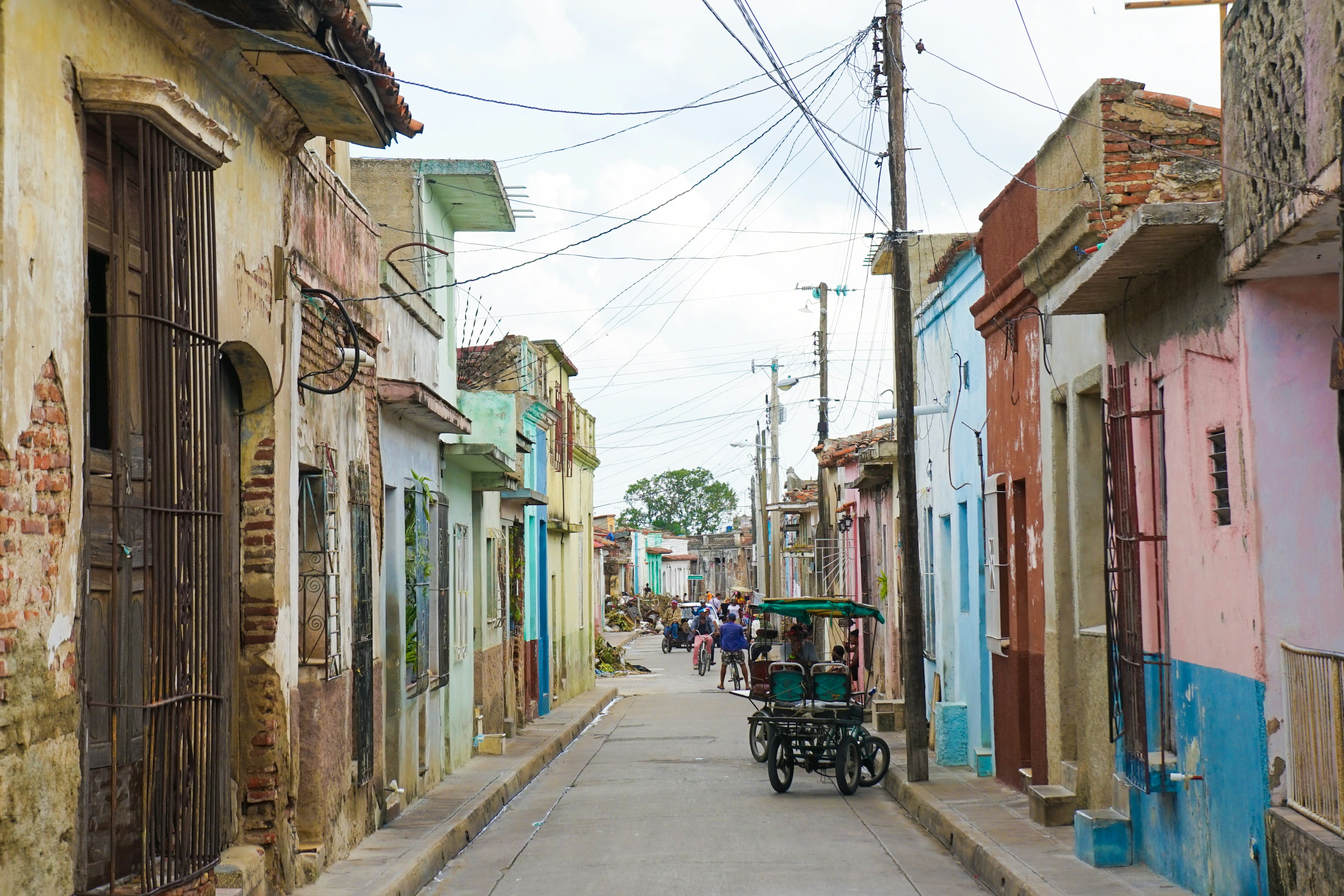 A narrow road in Camagüey, Cuba, lined with one-story buildings painted in pastel colors