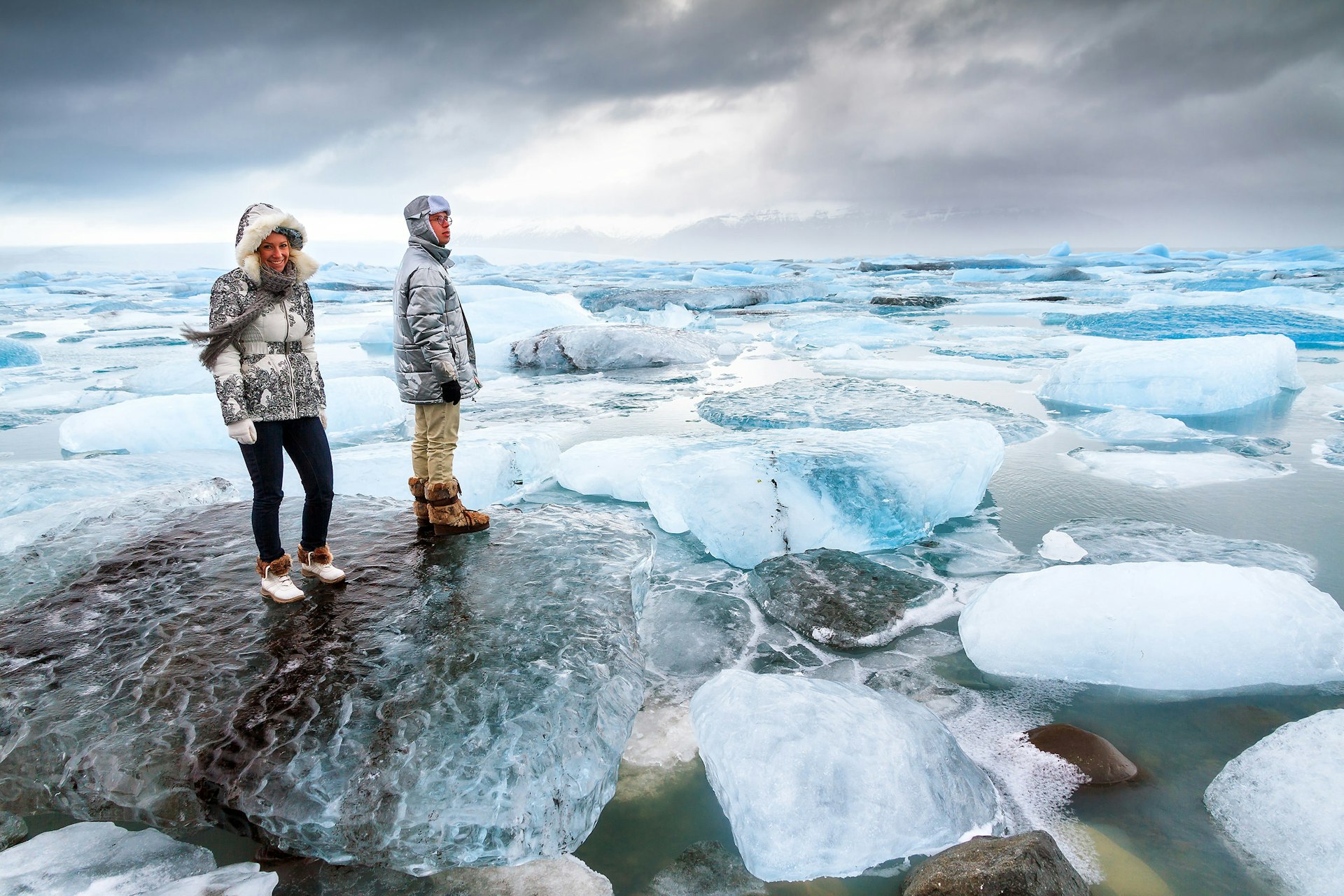 Tourists stand on the massive icebergs in lake Jokulsarlon in Iceland in winter