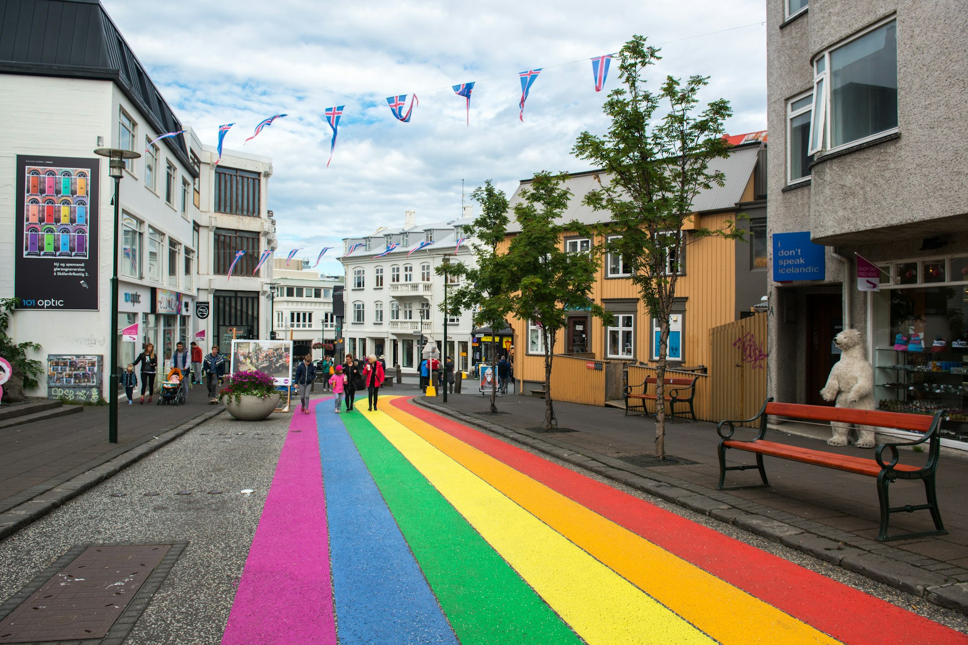 Pedestrian street painted with Pride colours and decorated with National Icelandic flags.