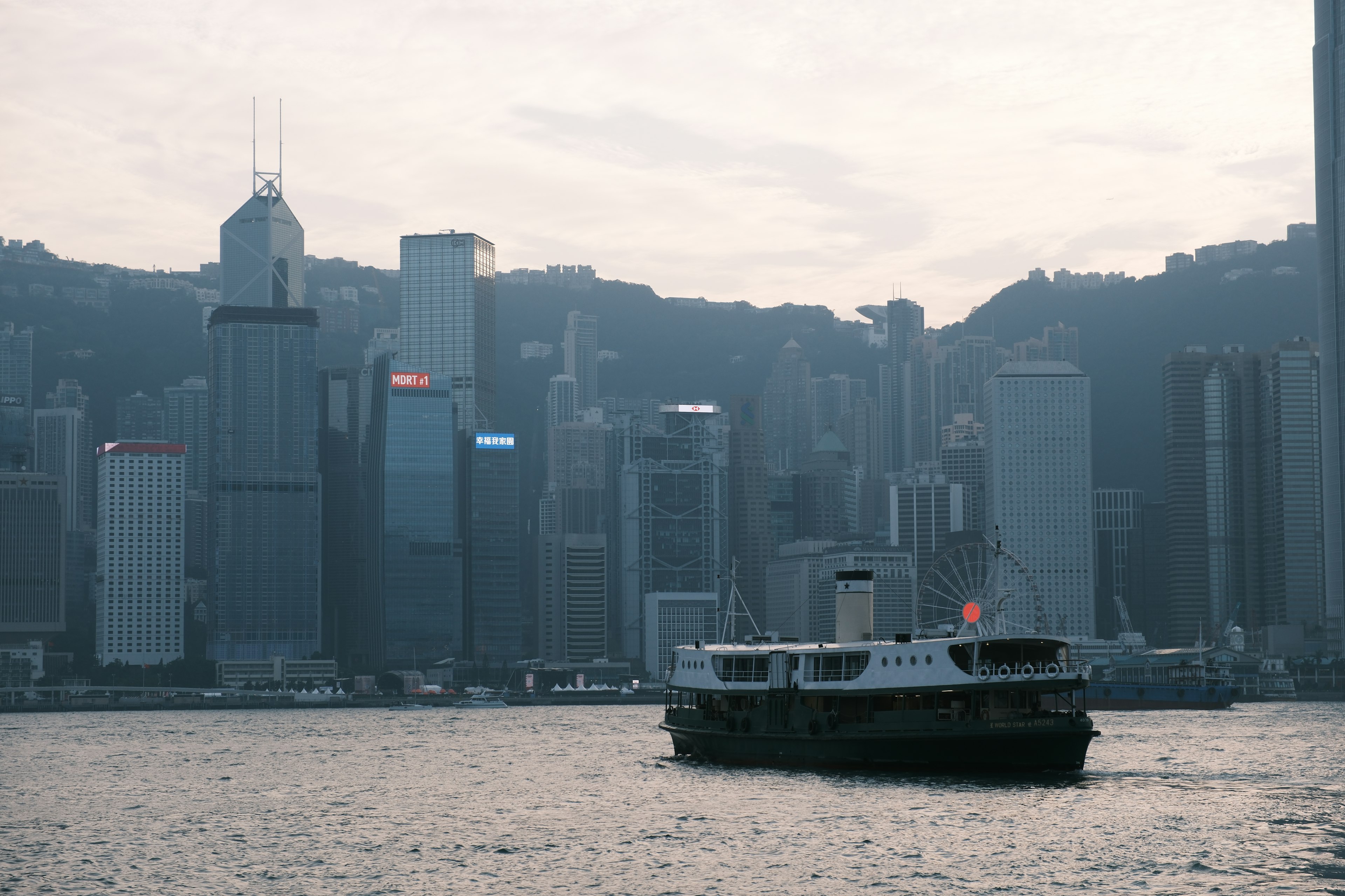 A ferry crosses a harbor in front of a city skyline