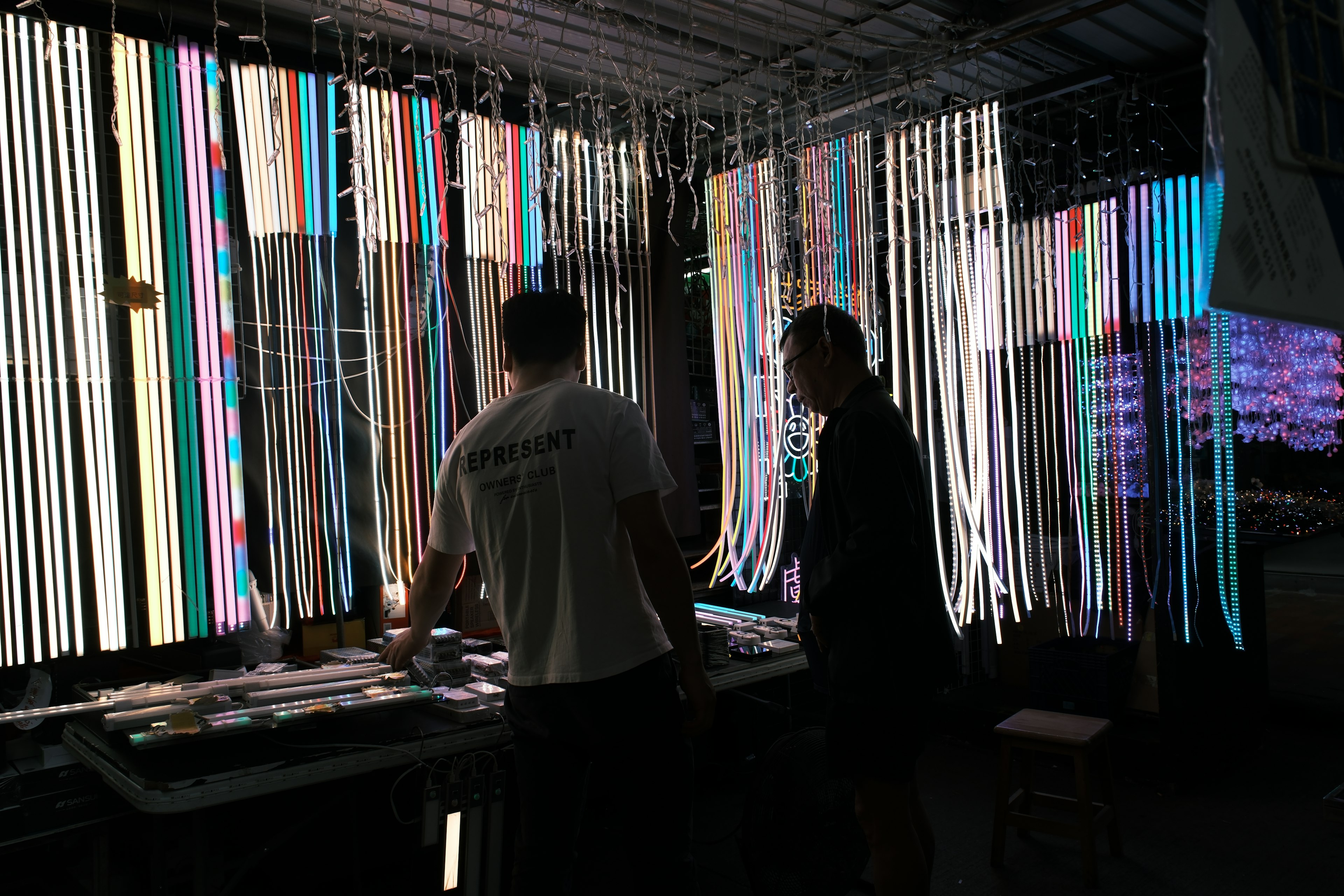 A market stall illuminated by rope lights, with two people in the foreground