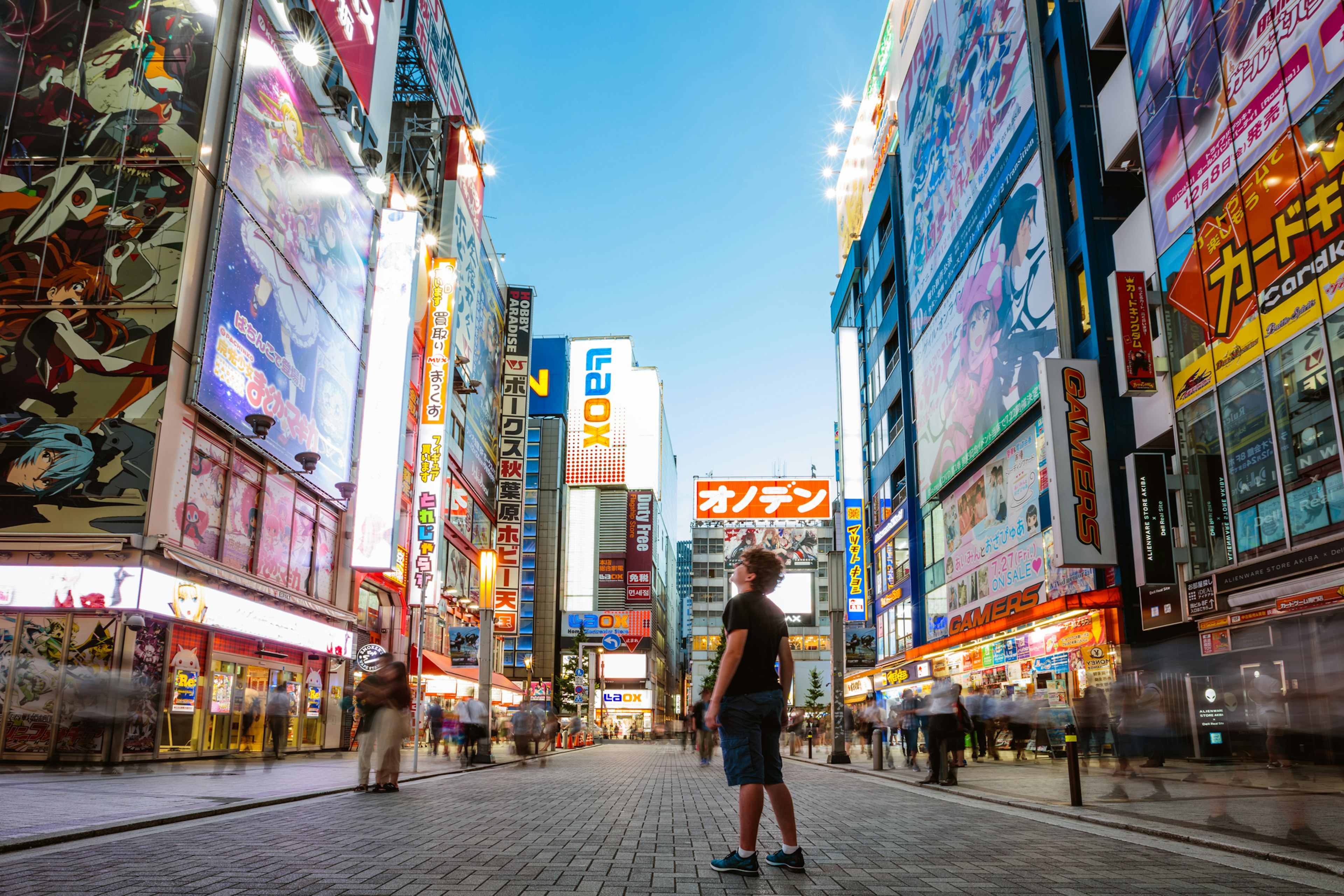 A teenager gazes upwards at the electric-light signs in a city street