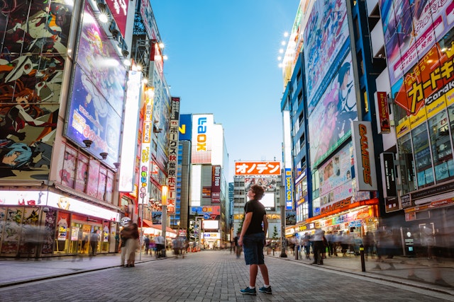 A teenager gazes upwards at the electric-light signs in a city street