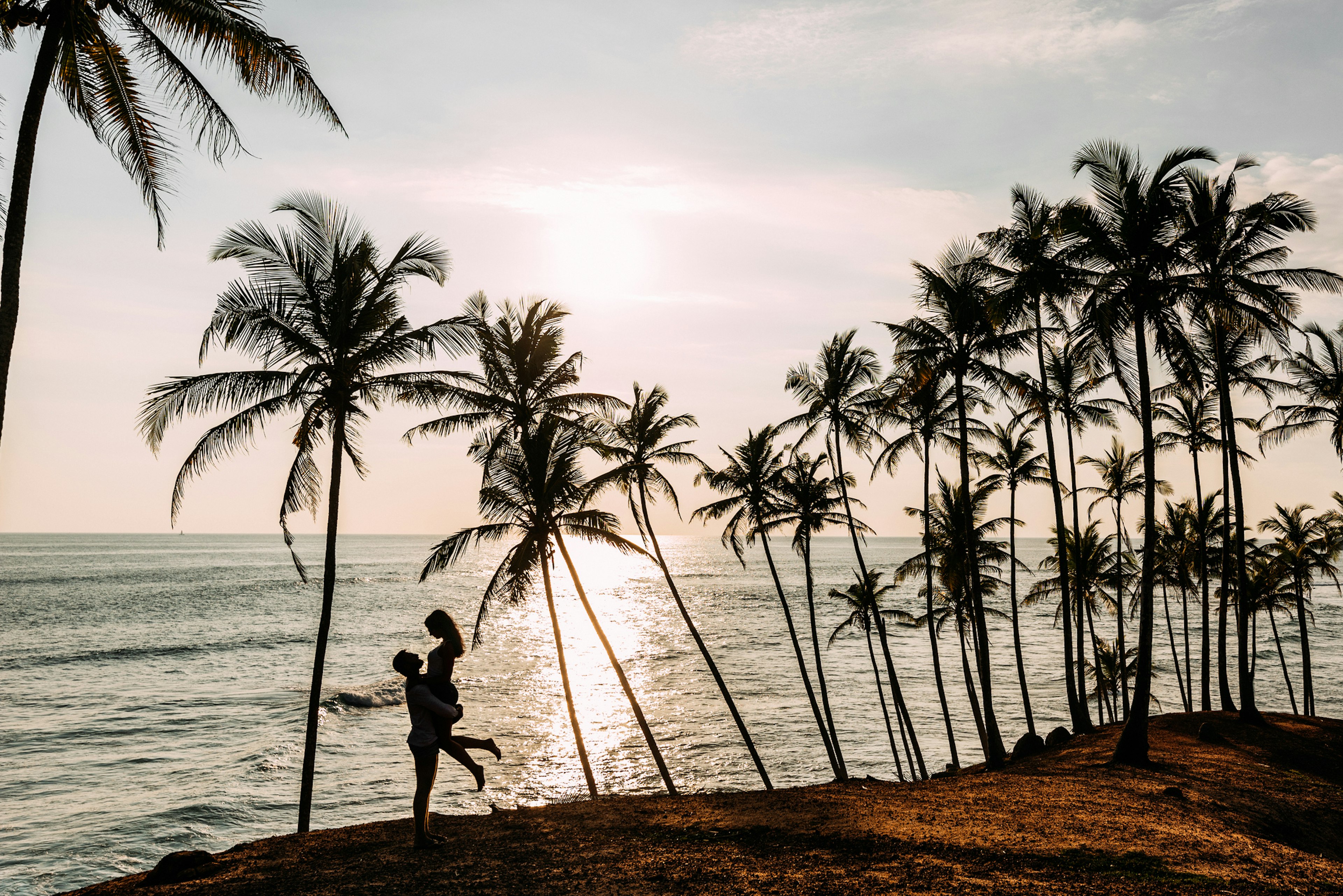 A couple in love meets a sunset on the sea among the palm trees. Boy and girl at sunset. Honeymoon on the Islands. Man and woman meet sunset.