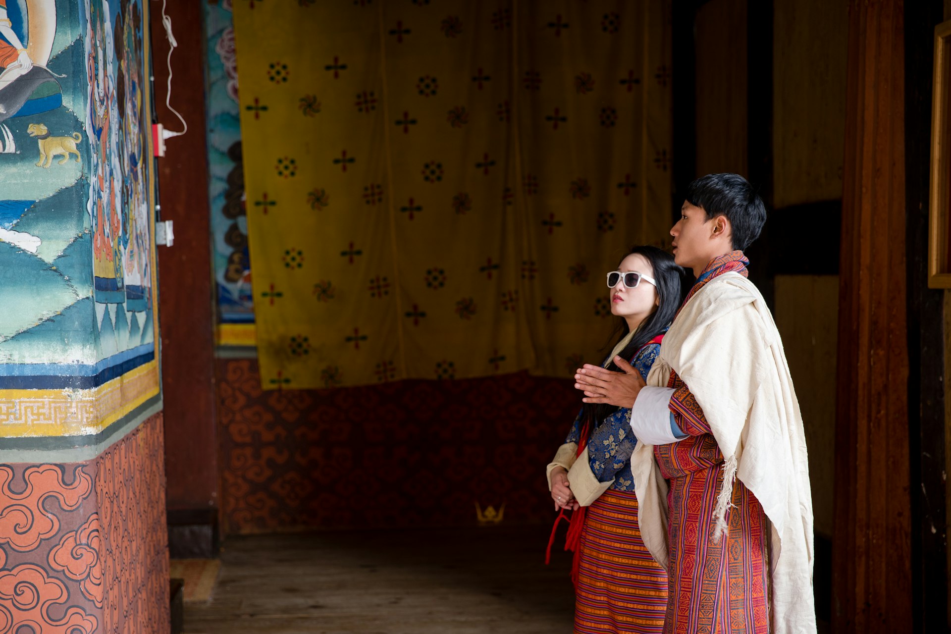 A young female tourist and a local guide looking at a painting on a wall in Paro, Bhutan