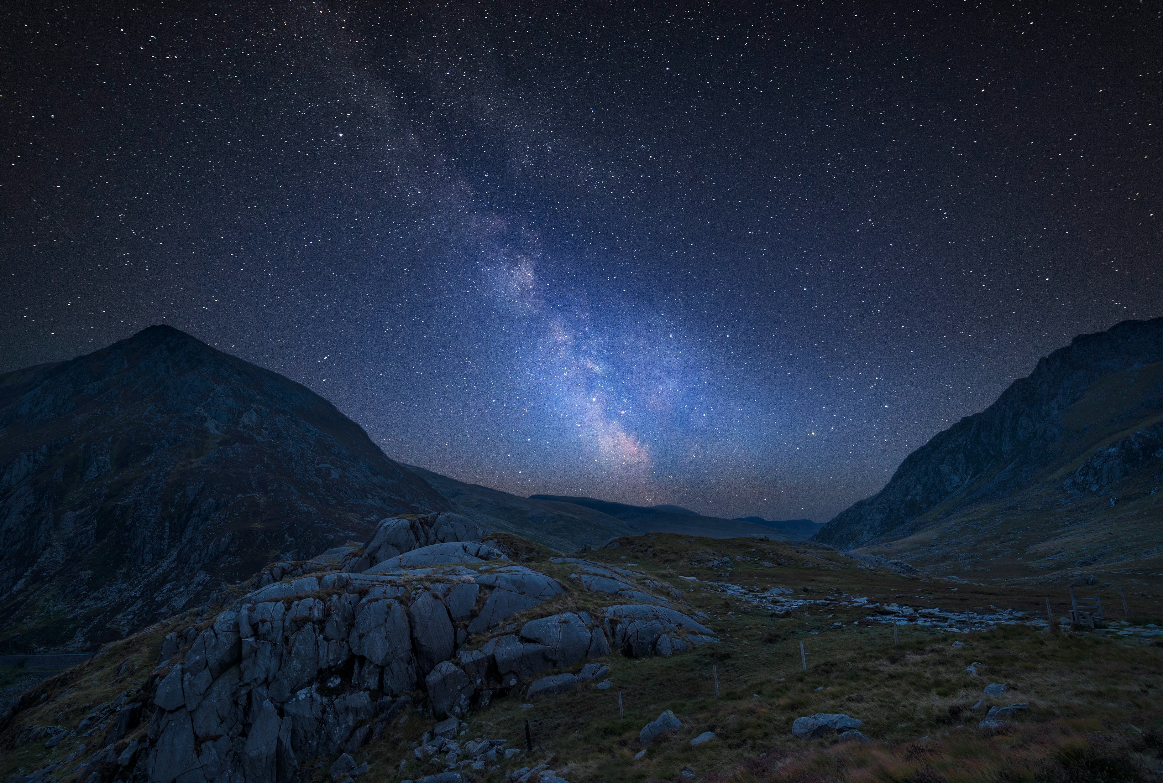 Stunning vibrant Milky Way composite image over Beautiful moody landscape image of a valley in Wales.